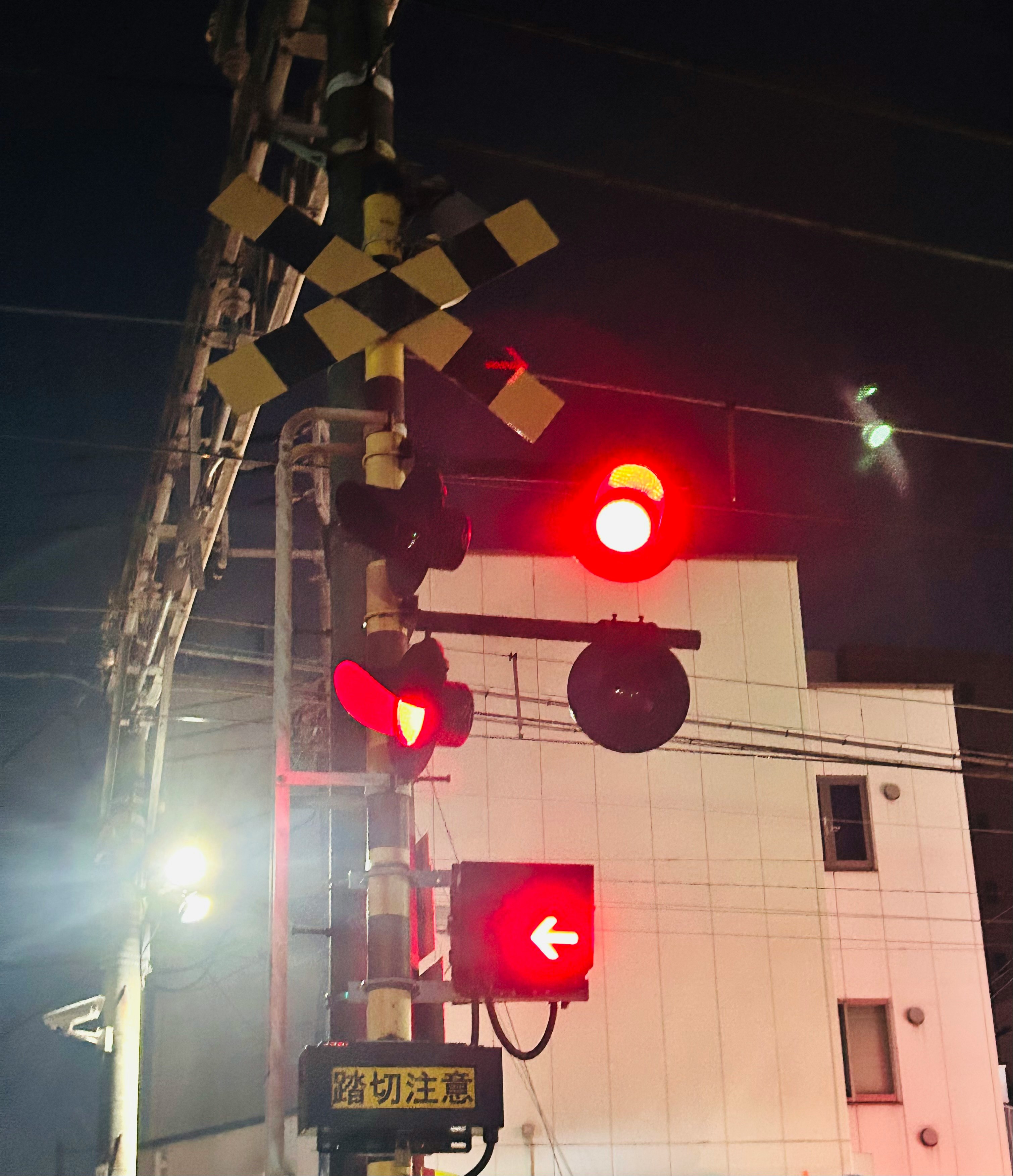 踏切の遮断機と赤い信号が点灯する夜道