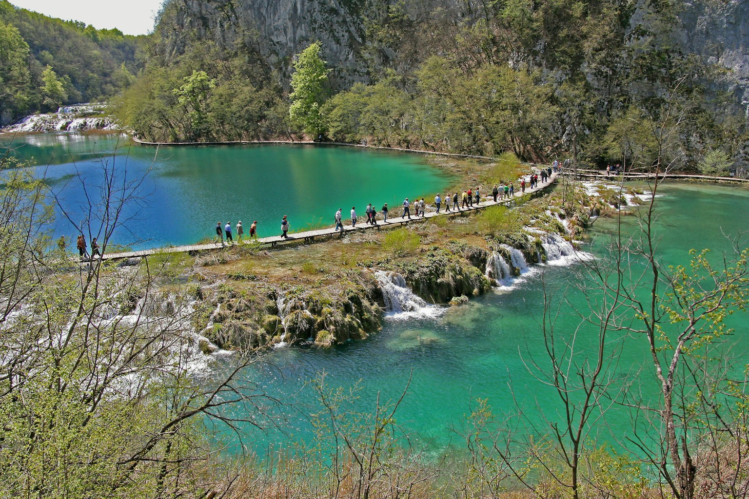 美丽的绿松石湖泊背景下，步道上有许多游客在走动