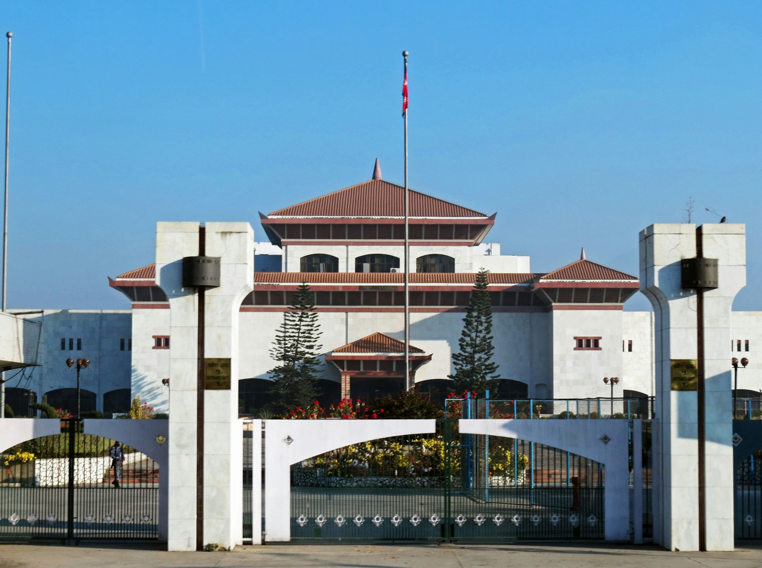 Tampilan luar bangunan putih dengan atap merah dan bendera
