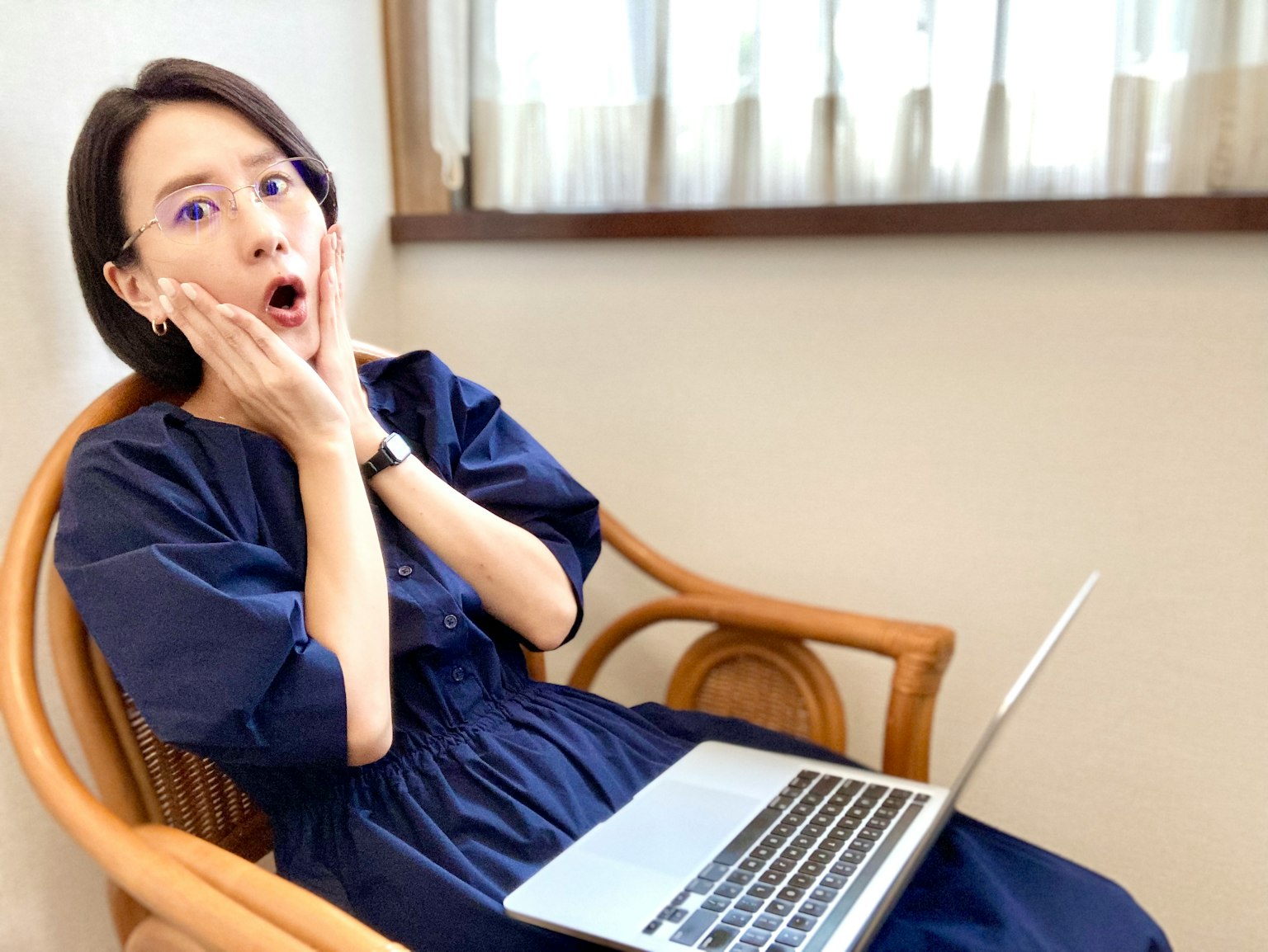 一位惊讶的女性坐在椅子上看着笔记本电脑