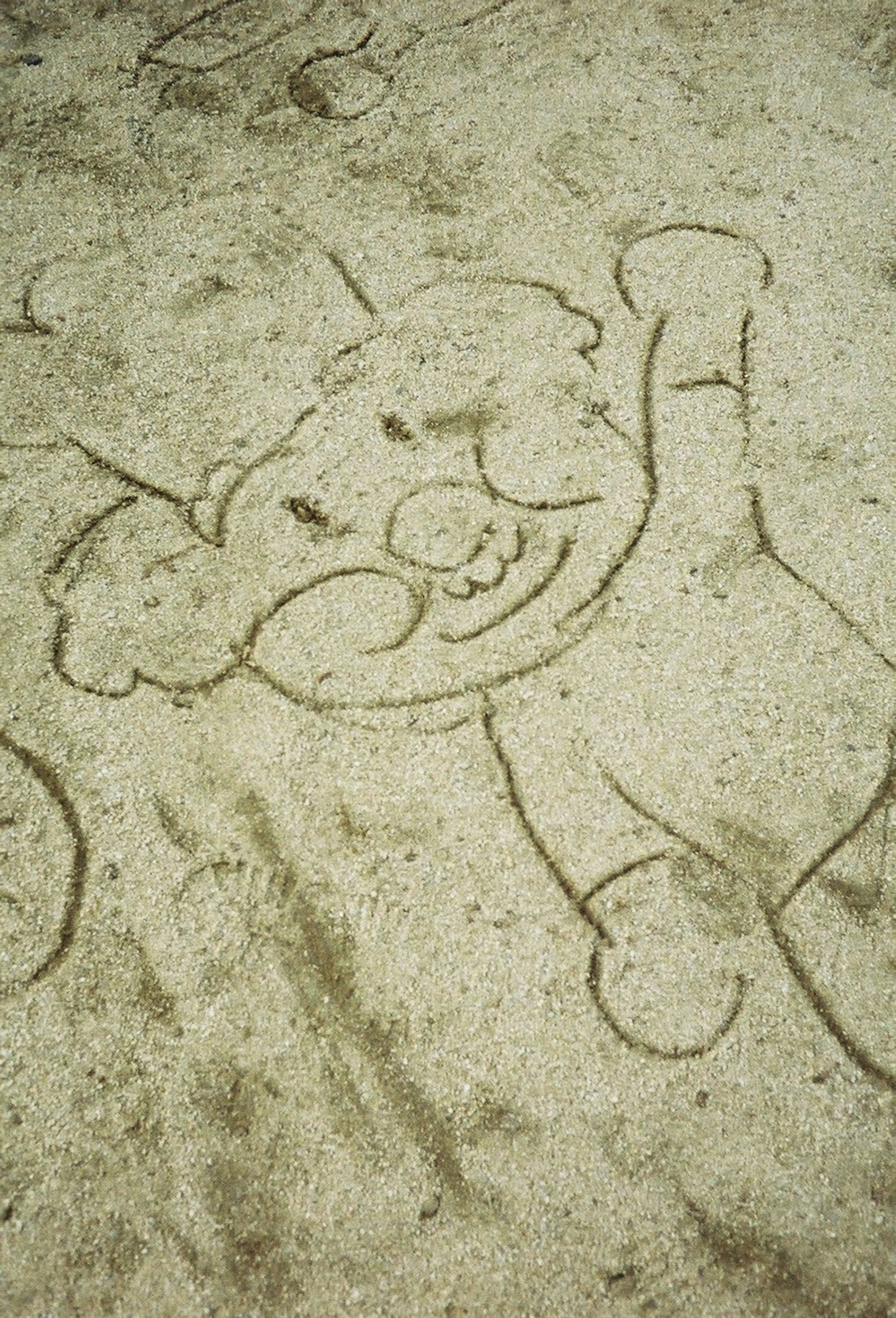 Eine lächelnde Clown-Illustration, die im Sand gezeichnet ist