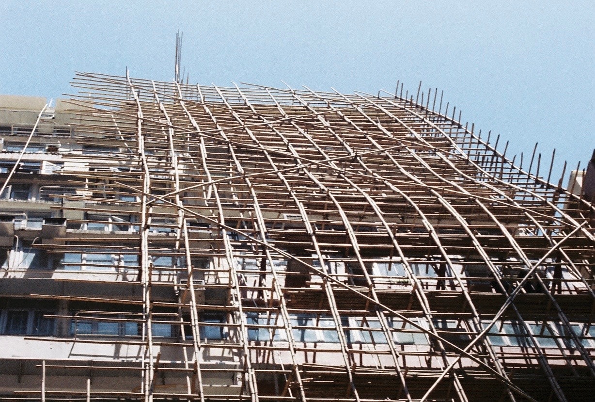 建物の屋根に組まれた鉄骨と足場の建設現場