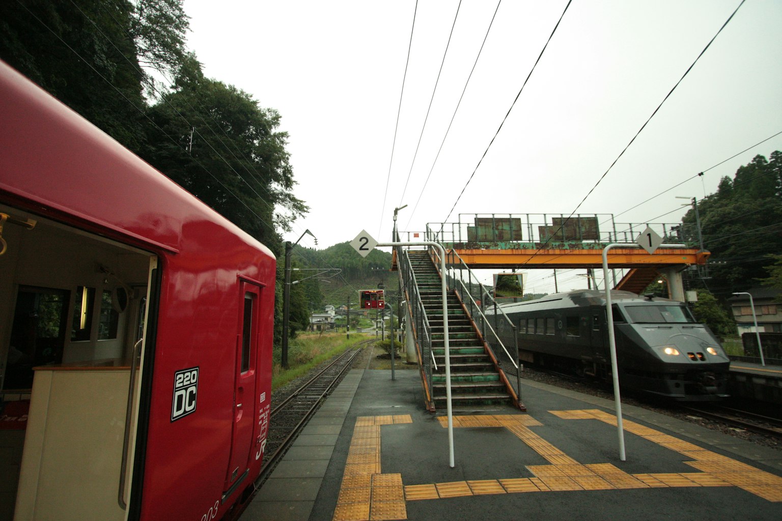 Pemandangan dengan kereta merah dan struktur stasiun dengan latar belakang hijau