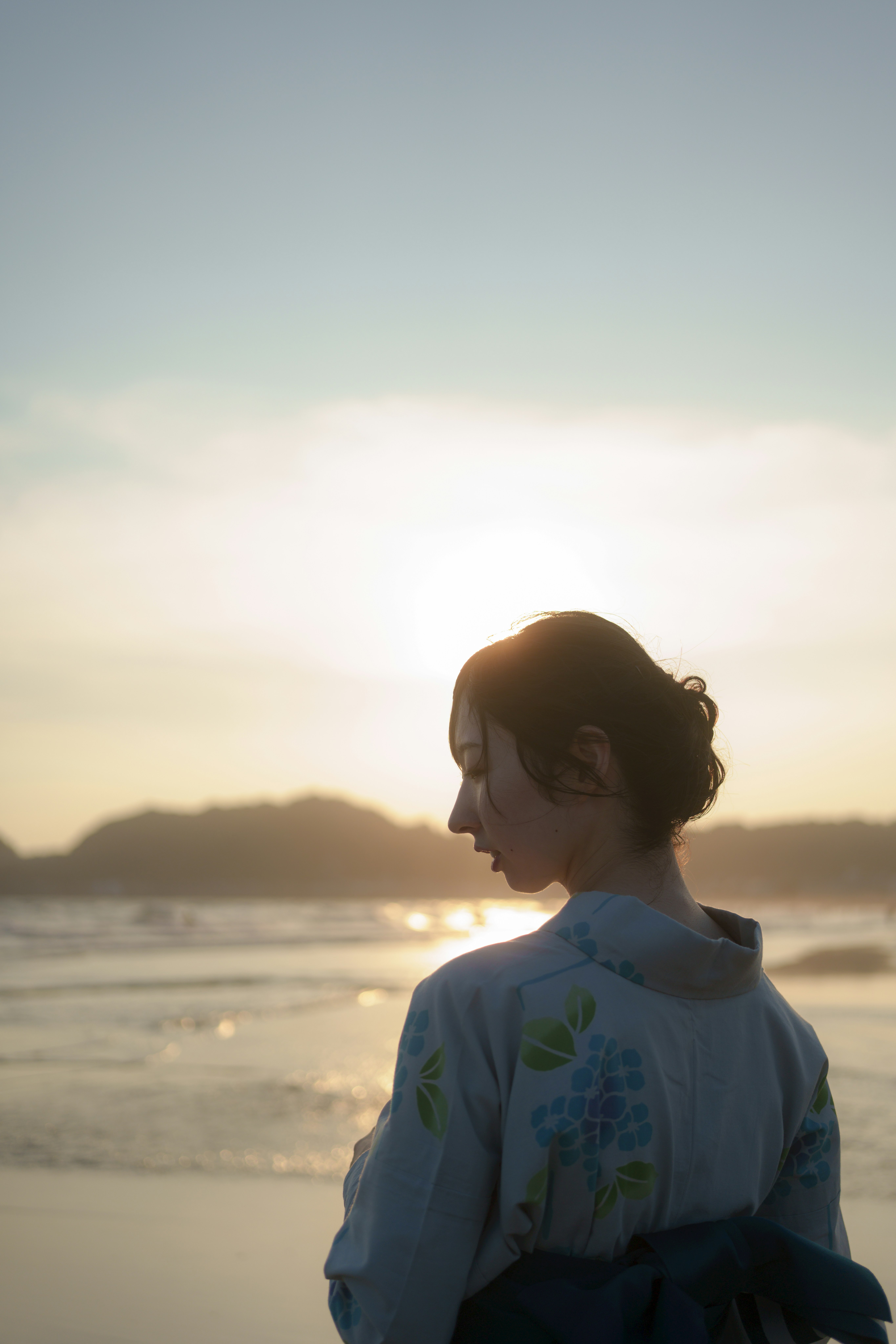 夕日の海辺で微笑む横顔の女性