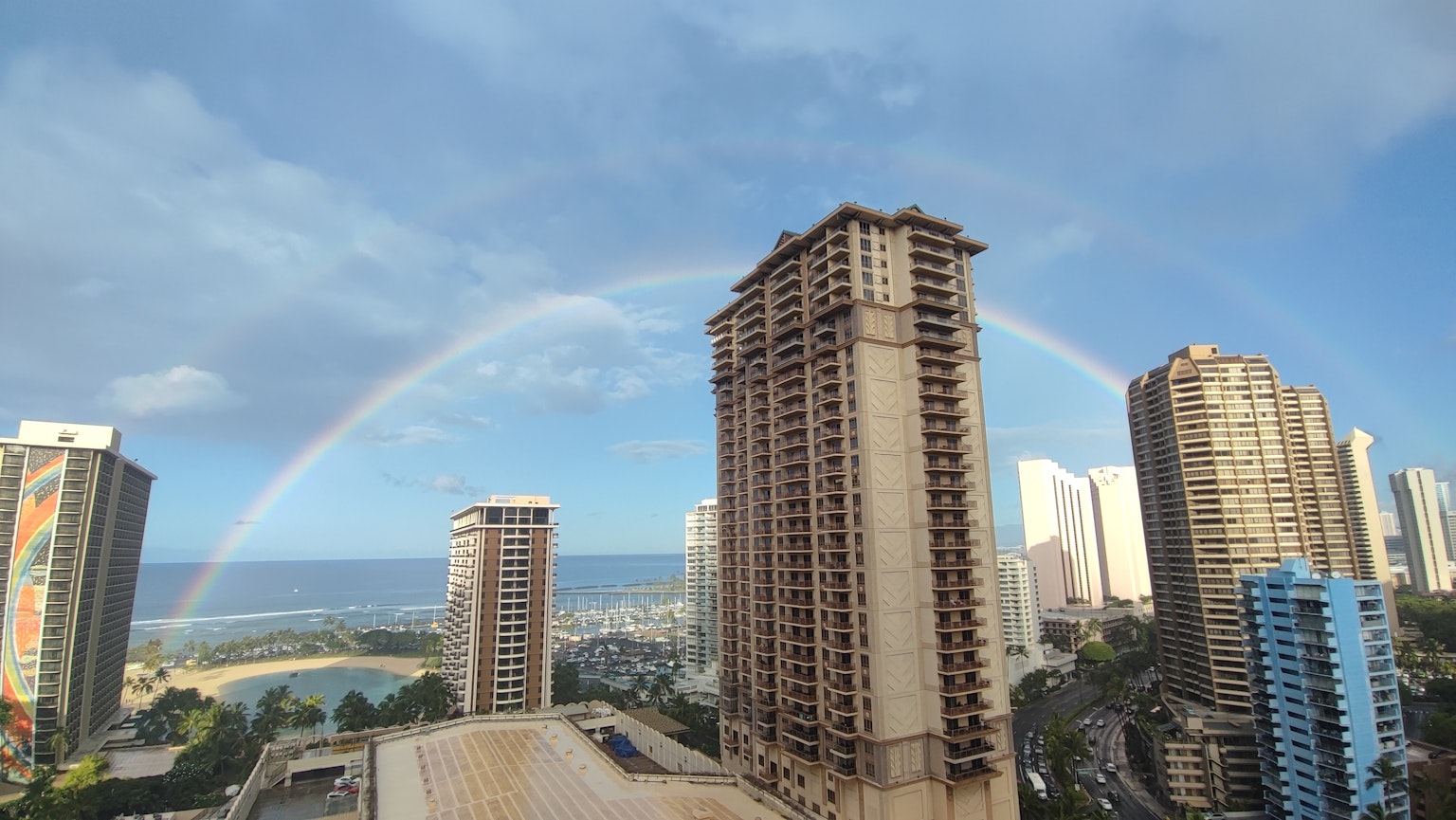 Arco iris sobre edificios altos y vista del océano