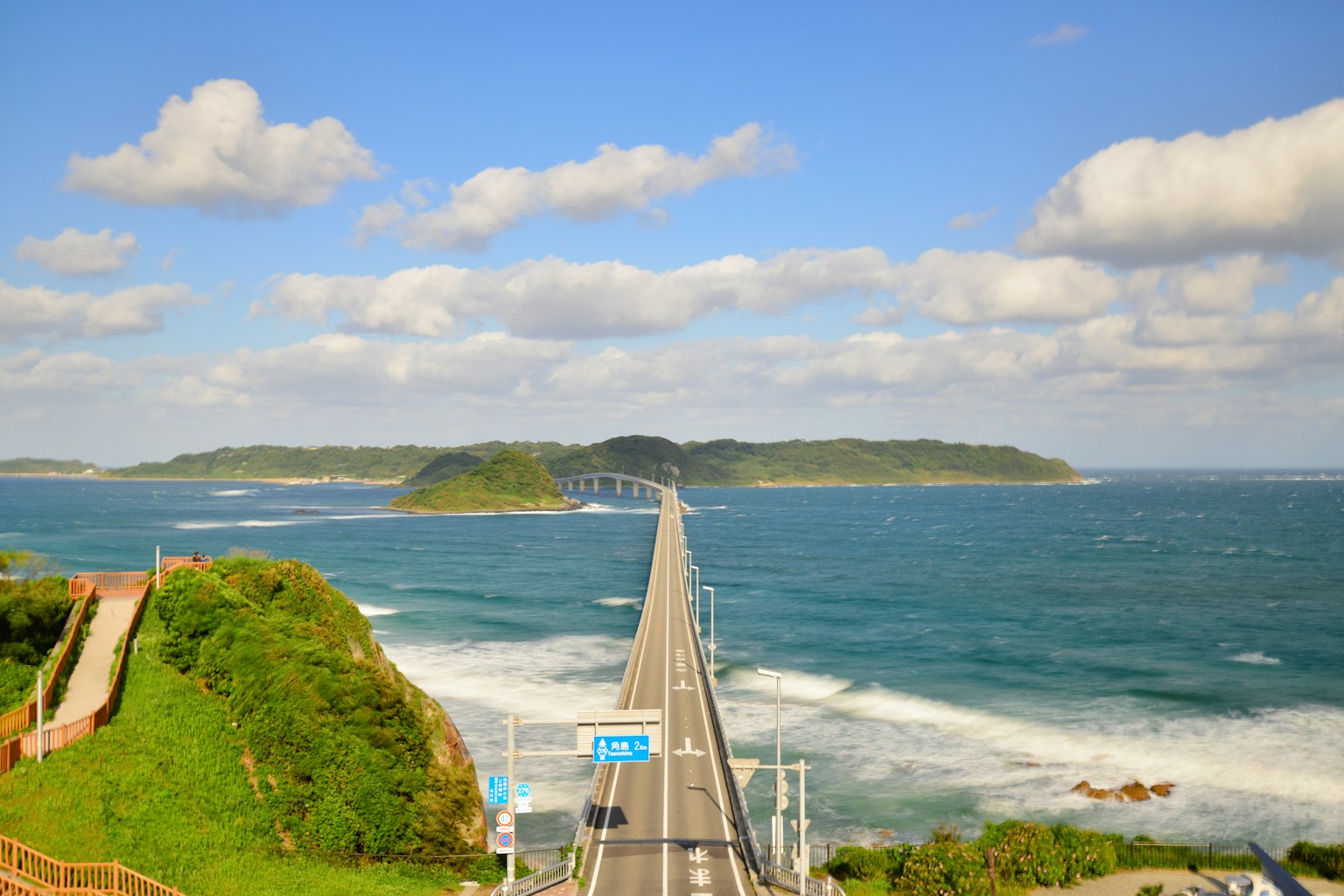 蓝色海洋和通往岛屿的桥的风景，白云为特色
