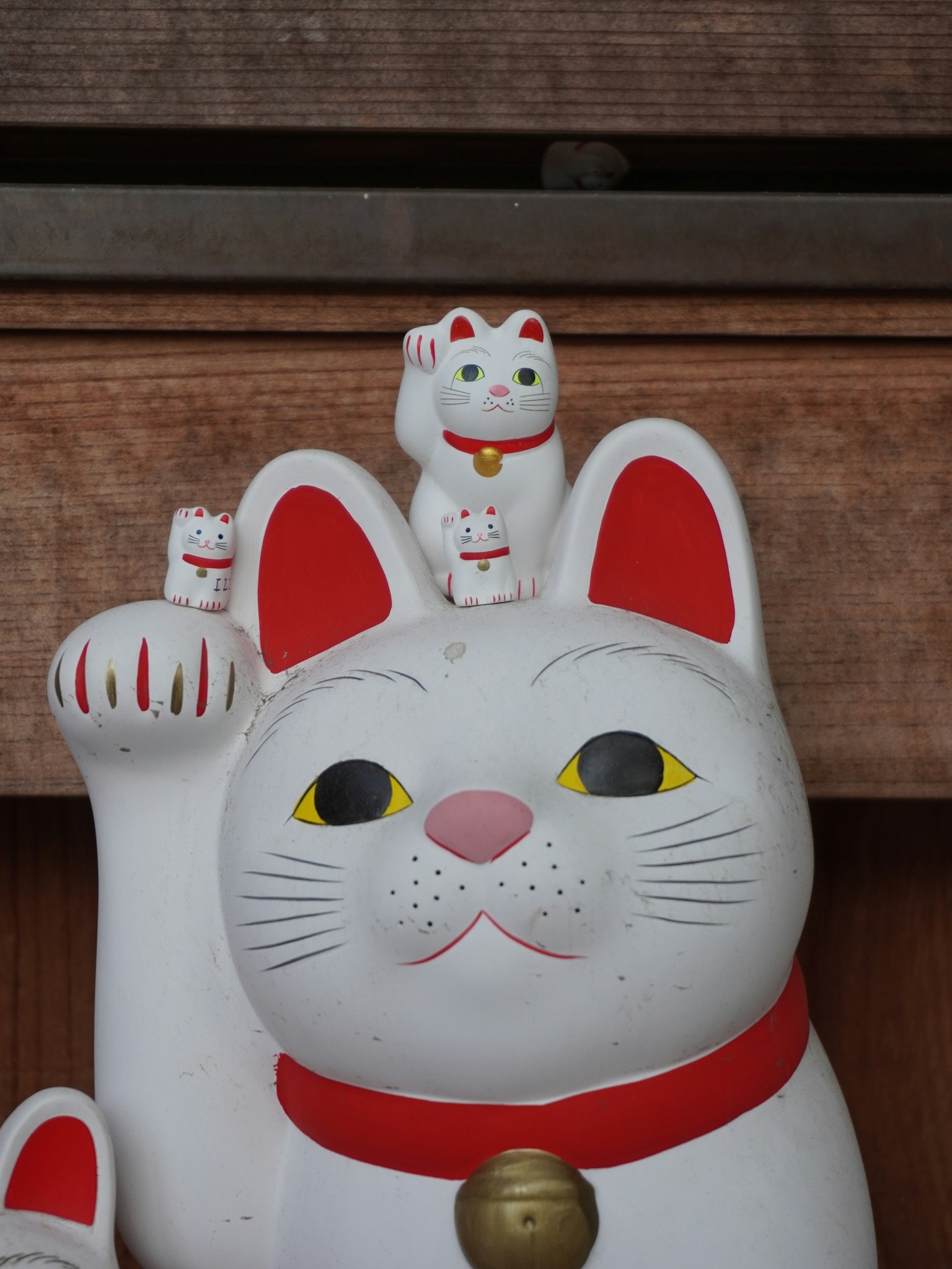 白い招き猫の像が手を挙げている上に小さな招き猫が二匹乗っている