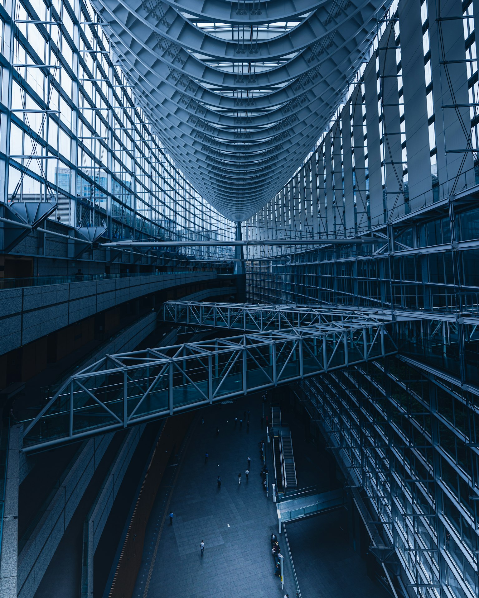 Interior bangunan modern dengan nada biru menampilkan langit-langit tinggi dan dinding kaca