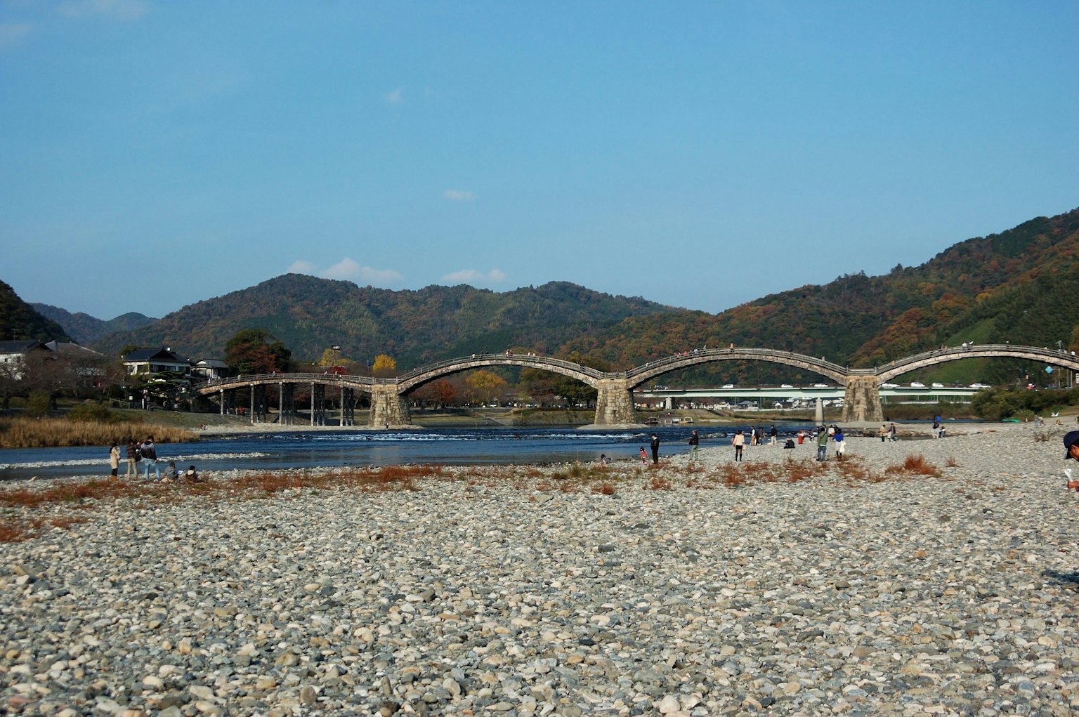 Ein malerischer Fluss mit einer Bogenbrücke vor sanften Hügeln