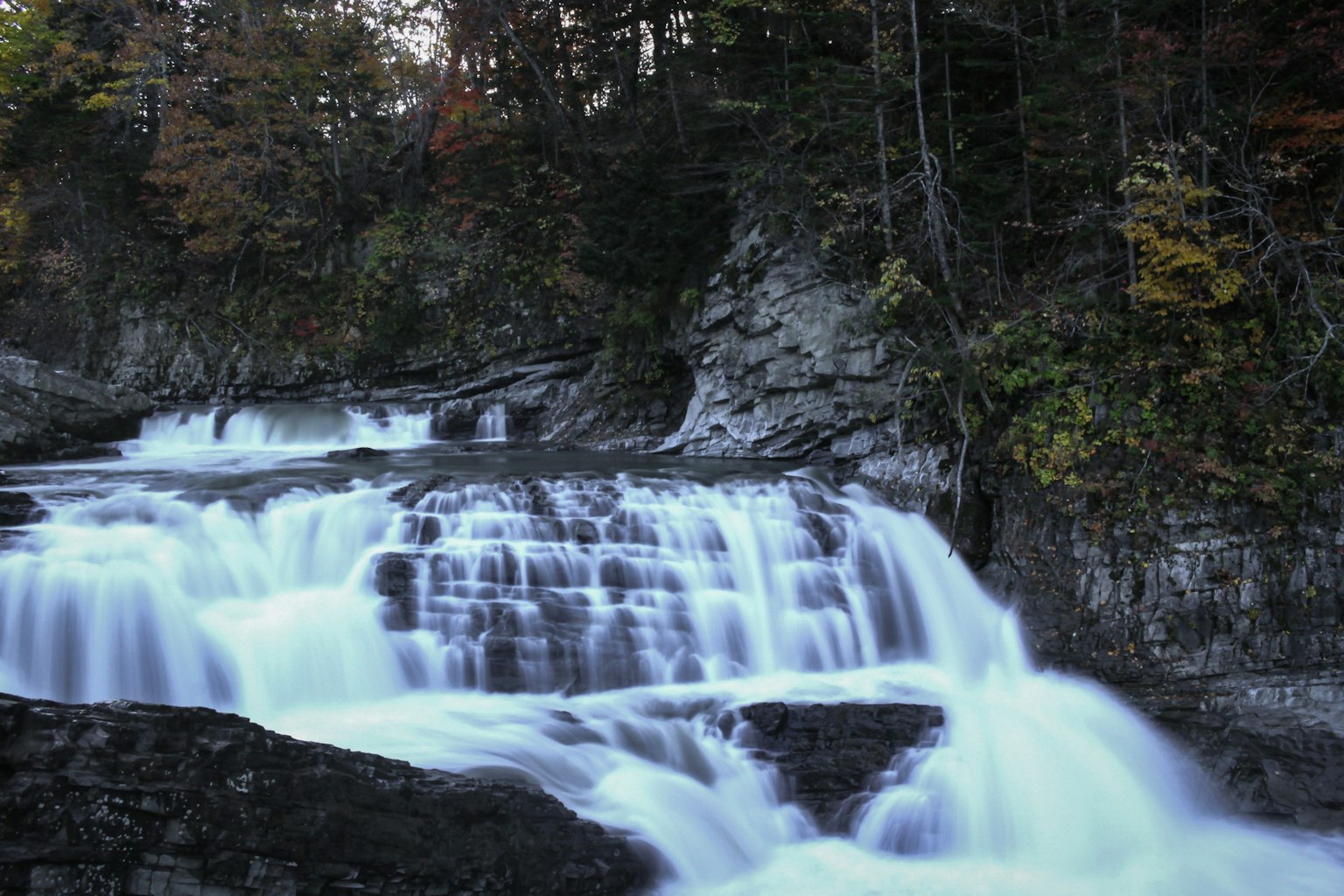 Schöner Wasserfall, der über Felsen fließt, umgeben von Bäumen