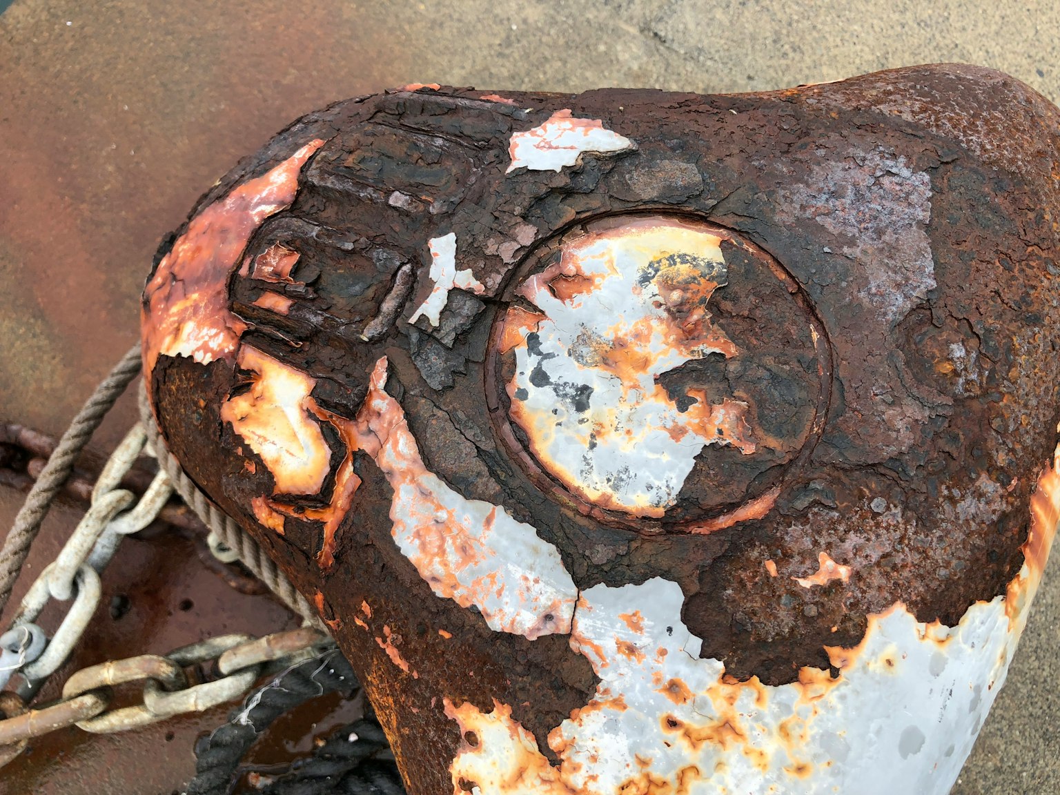 A close-up of a rusty metal anchor with a chain partially visible