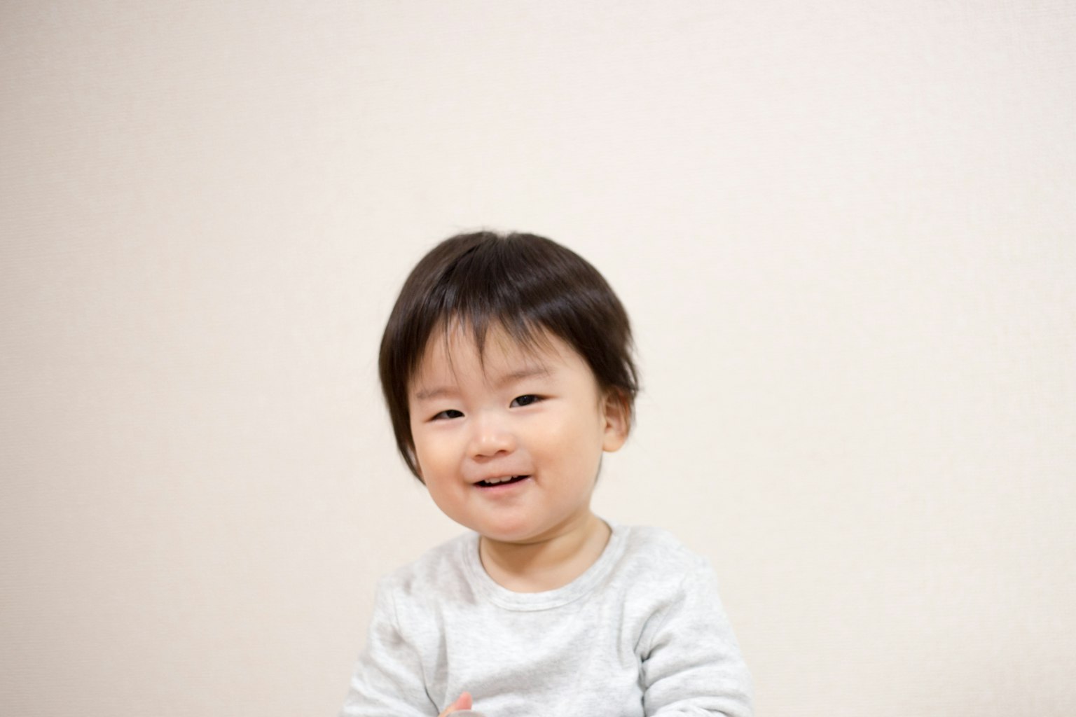 เด็กยิ้มที่นั่งอยู่หน้ากำแพงสีขาว