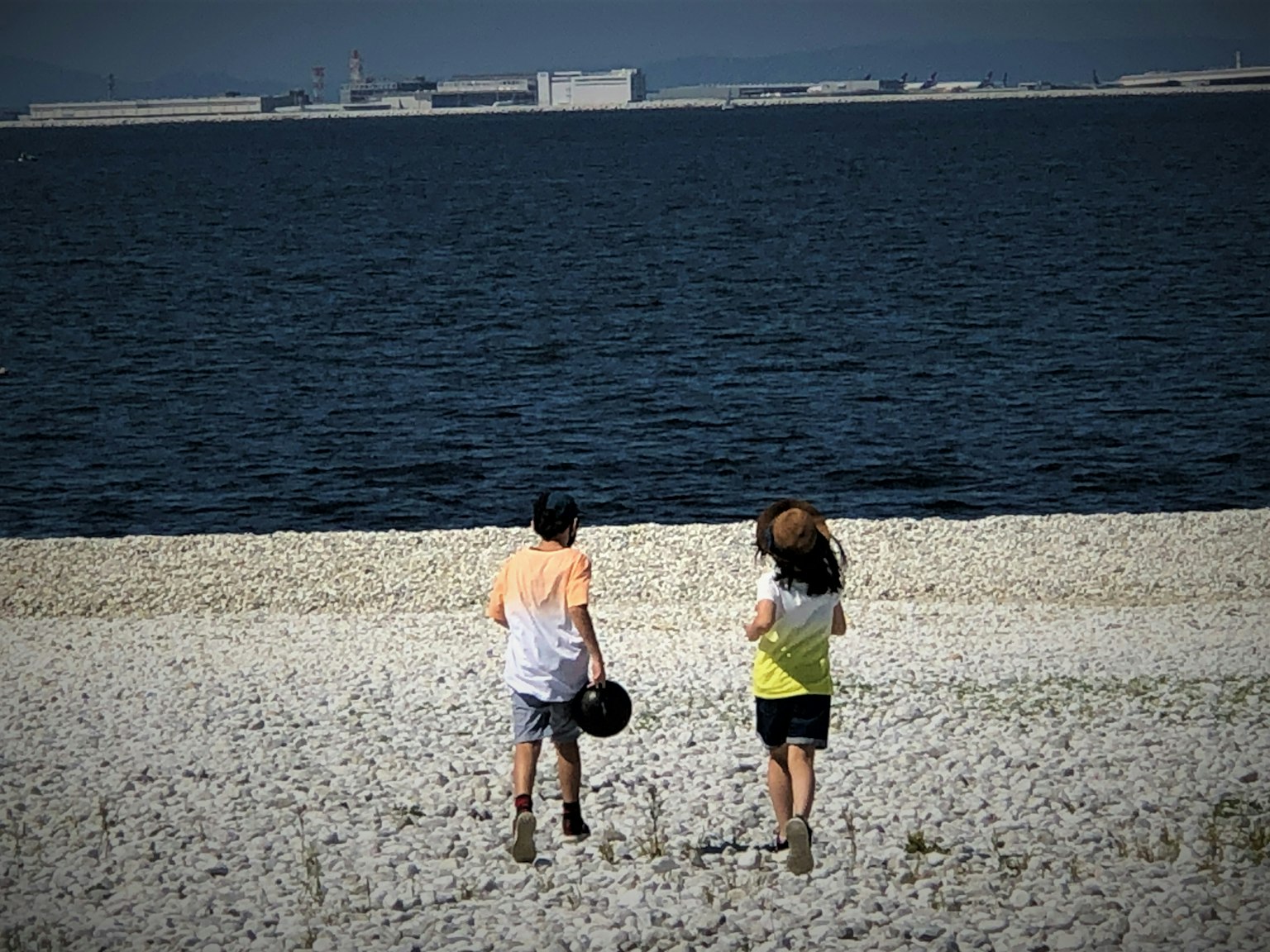 两个人在卵石海滩上散步，海洋和天空在背景中