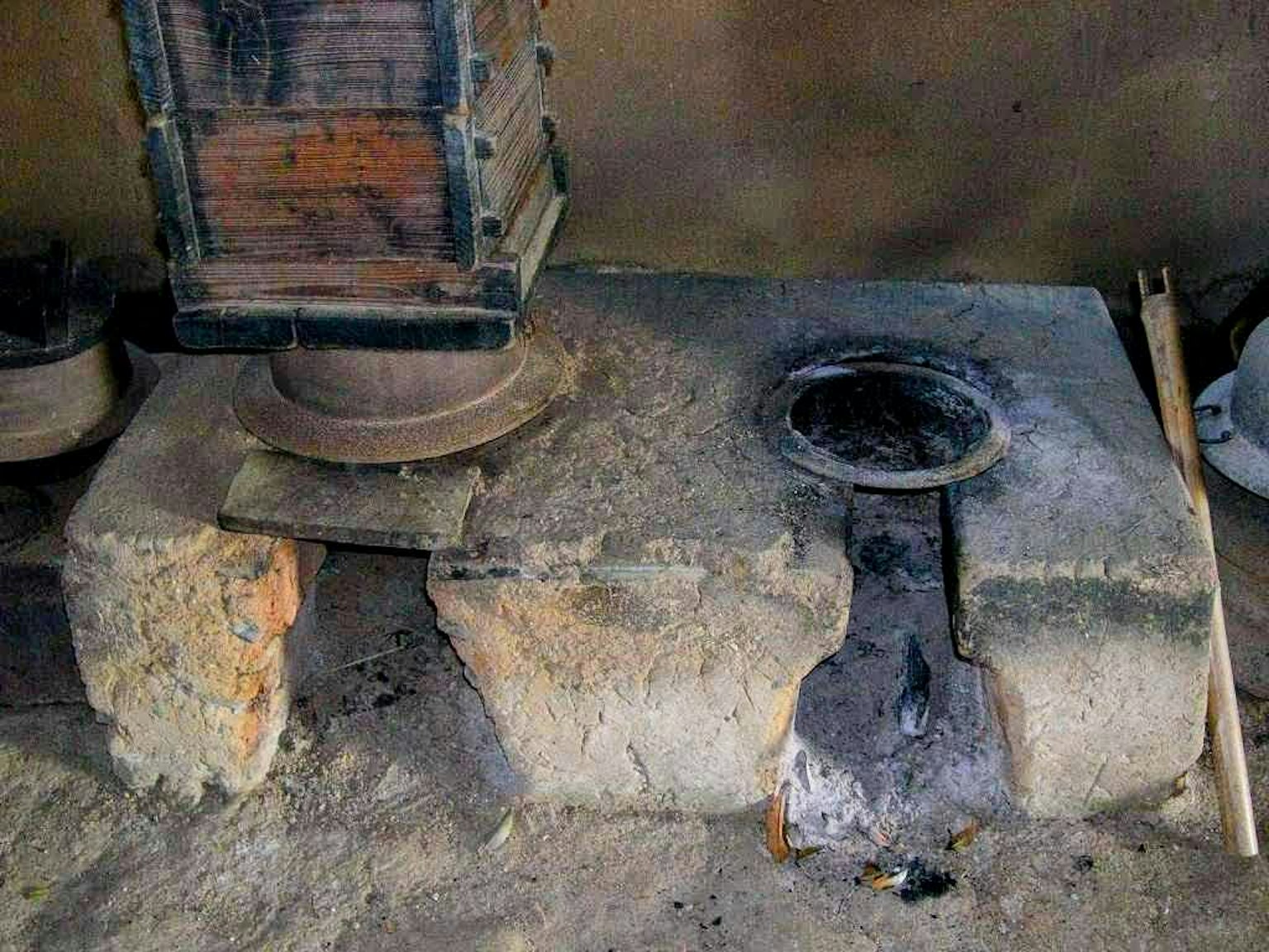 Sebuah kompor batu tua dengan peralatan masak kayu di dekatnya