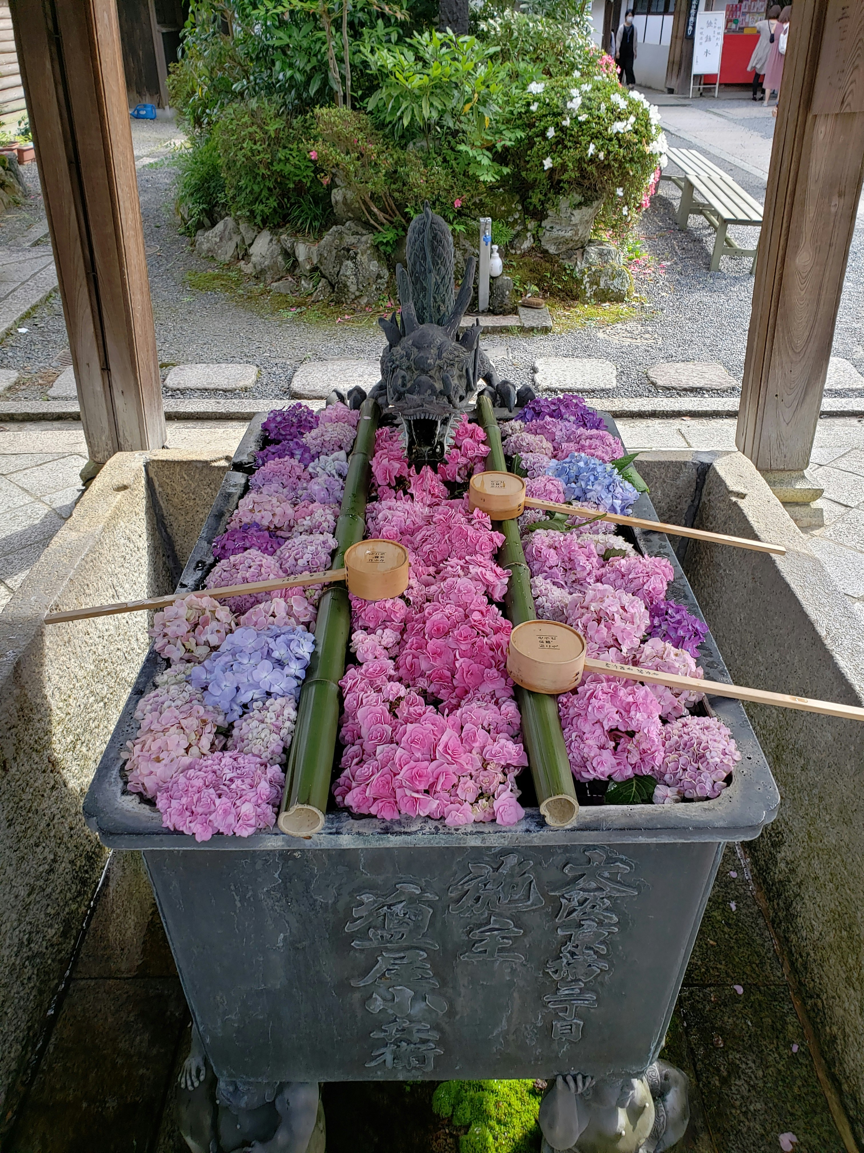 Colorful flowers floating in a stone water basin at a Japanese shrine