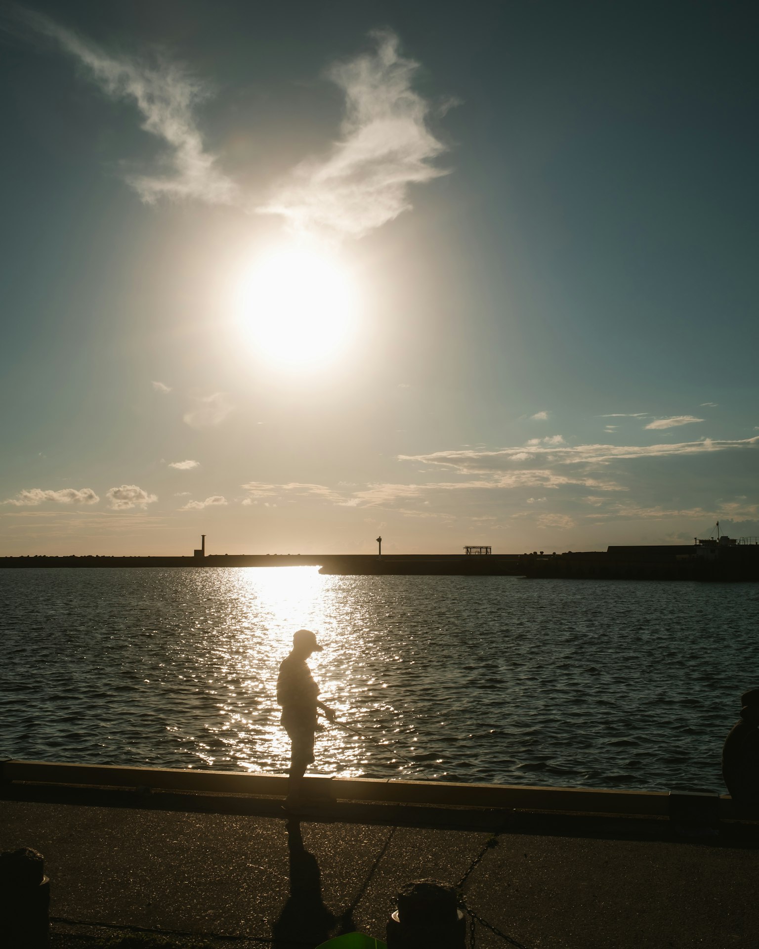 海辺で夕日を背に立つ人影と水面の反射