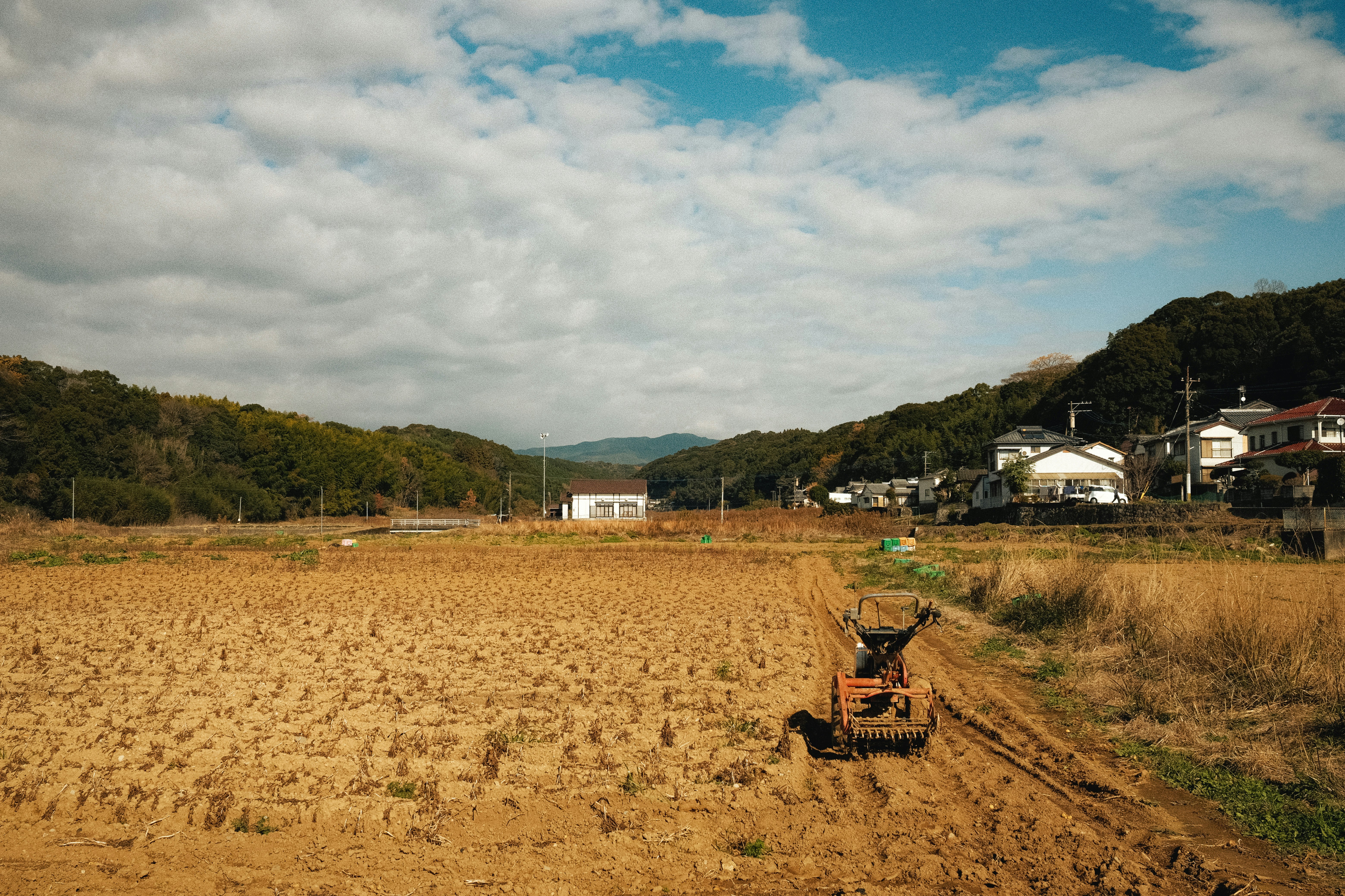 rural farmland rows with farm equipment in a countryside landscape