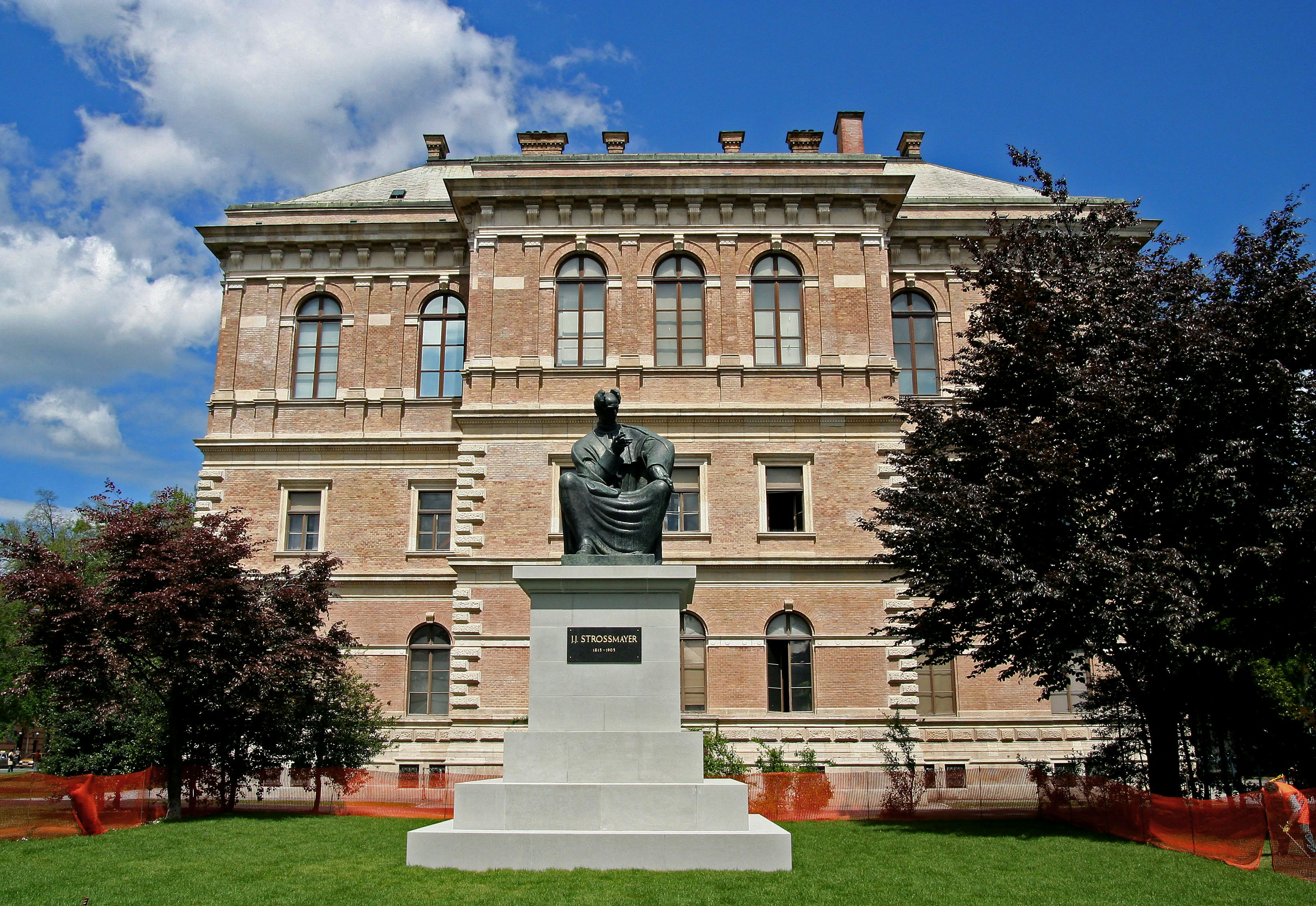 bronze statue on a lawn in front of a brick building