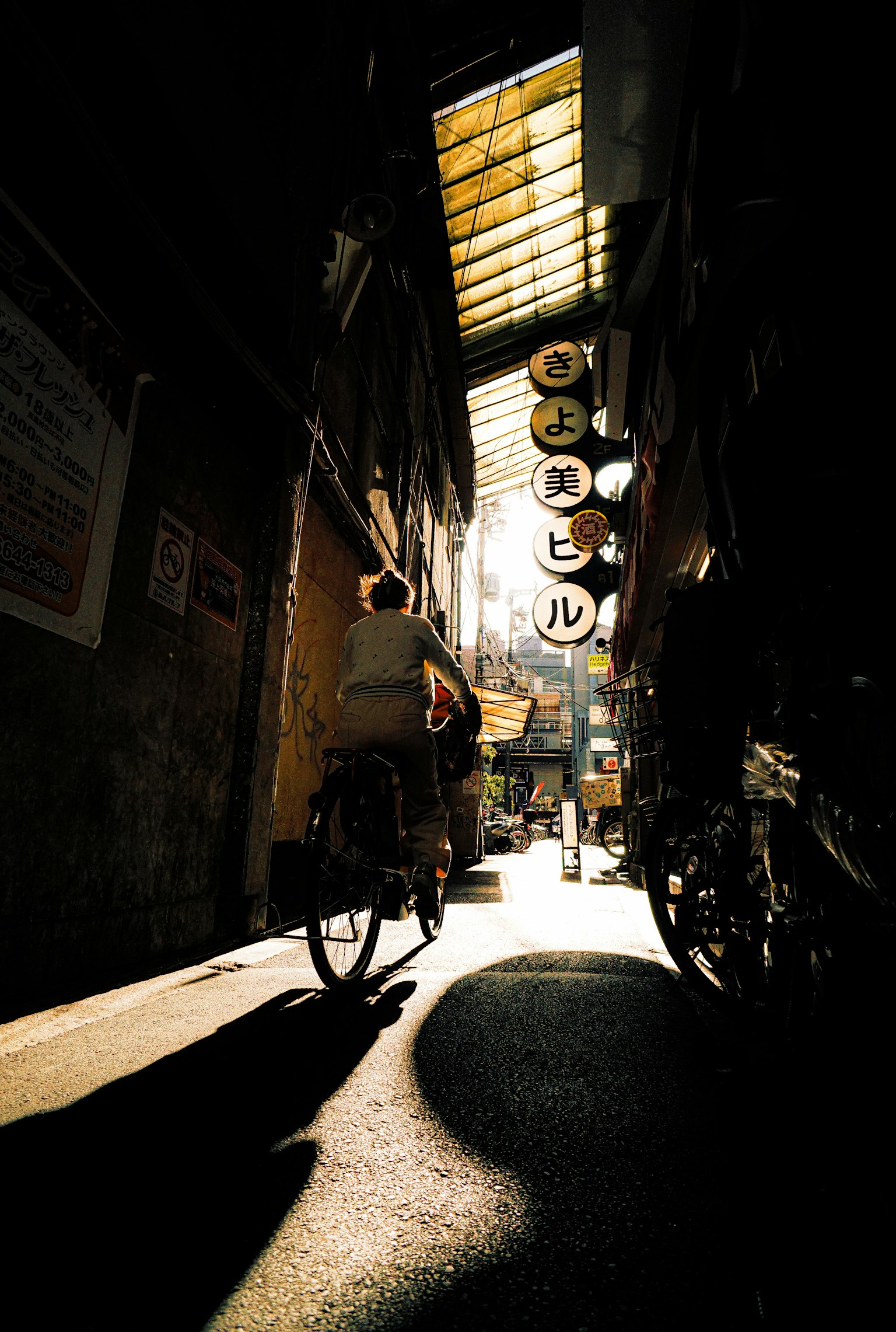 Une personne faisant du vélo dans une ruelle étroite avec de la lumière du soleil qui pénètre