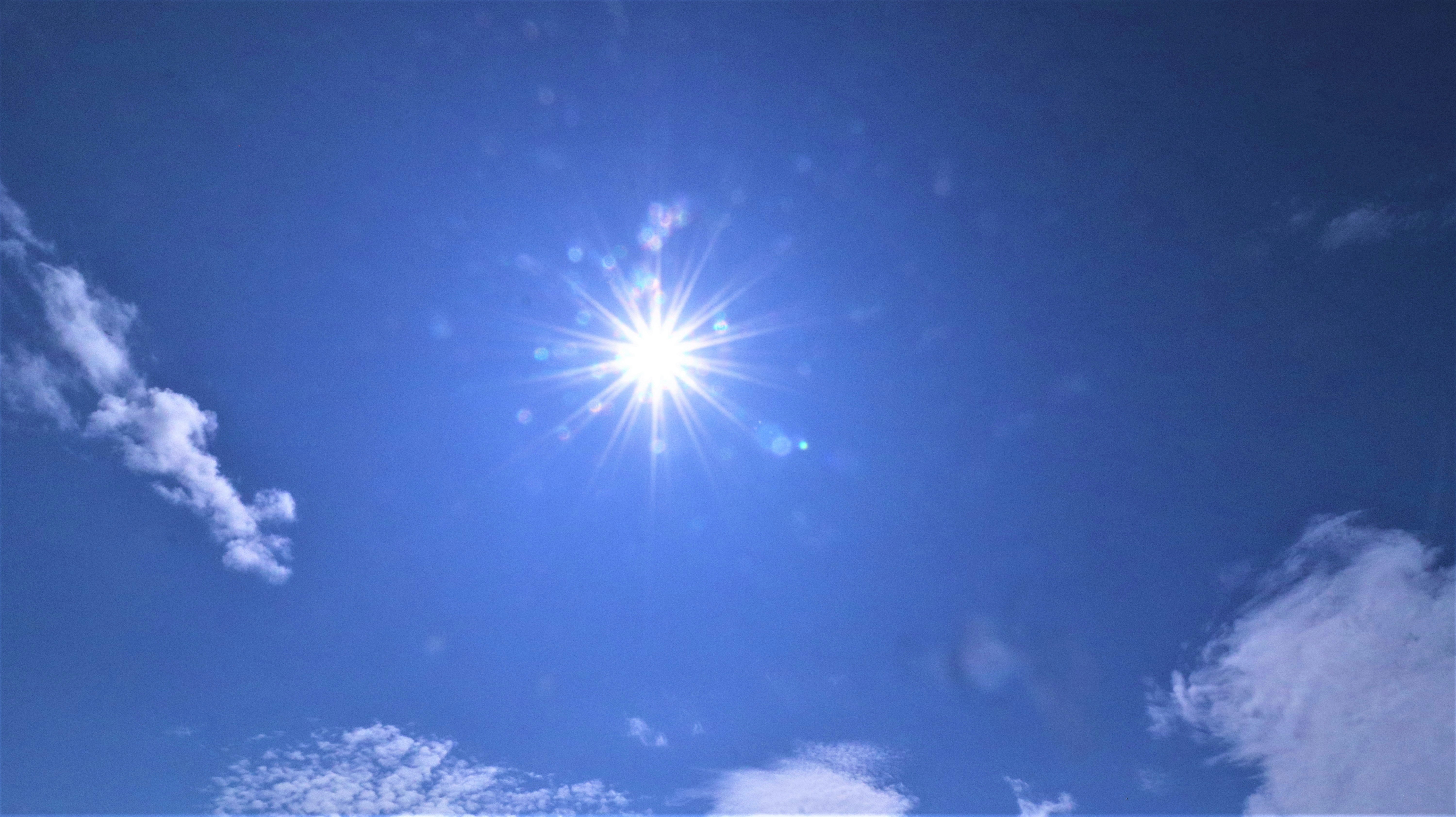 青空に輝く太陽と雲の広がる空