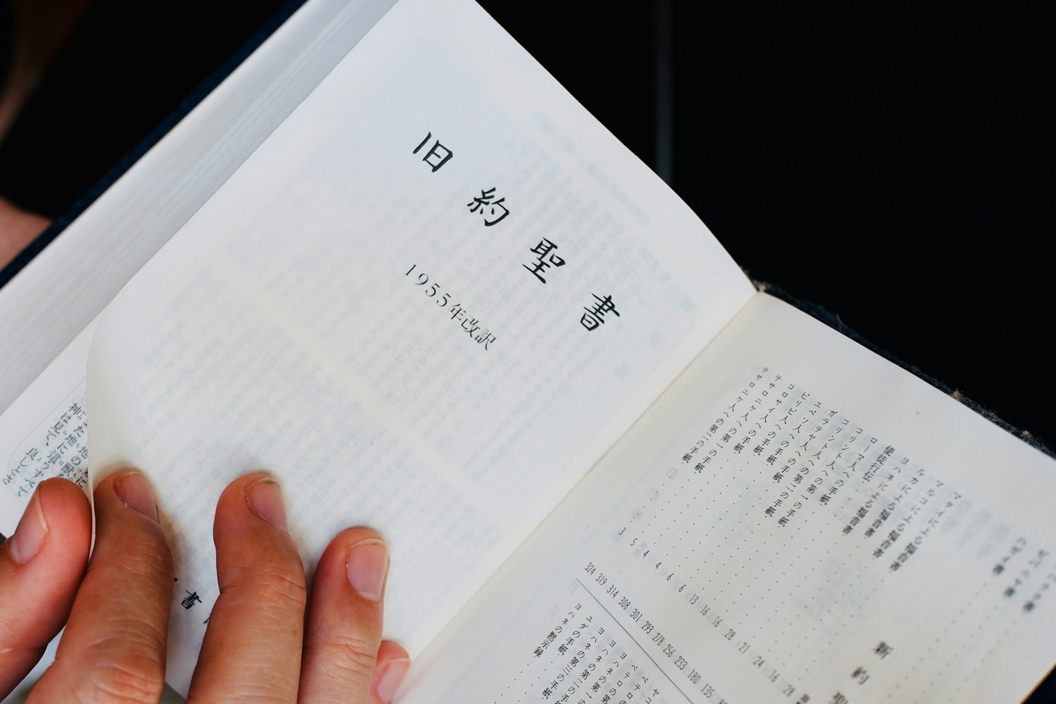 手握一本书的特写，书页上有日文文本和复古印刷风格