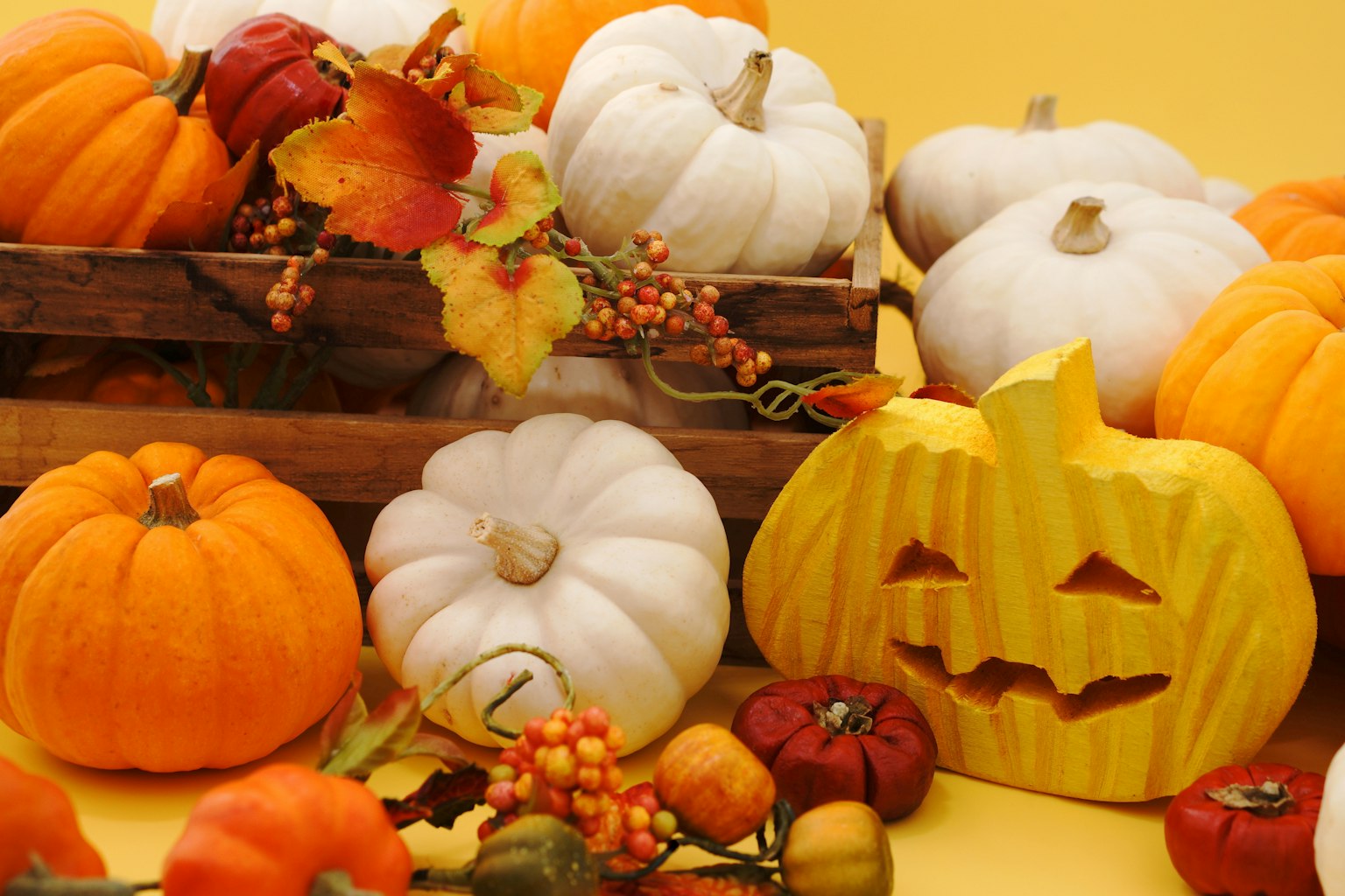 Una scena di decorazione autunnale con zucche arancioni e bianche e una zucca gialla intagliata