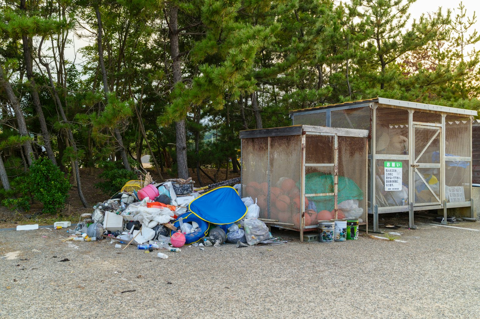 A pile of scattered trash near a simple wooden dumpster
