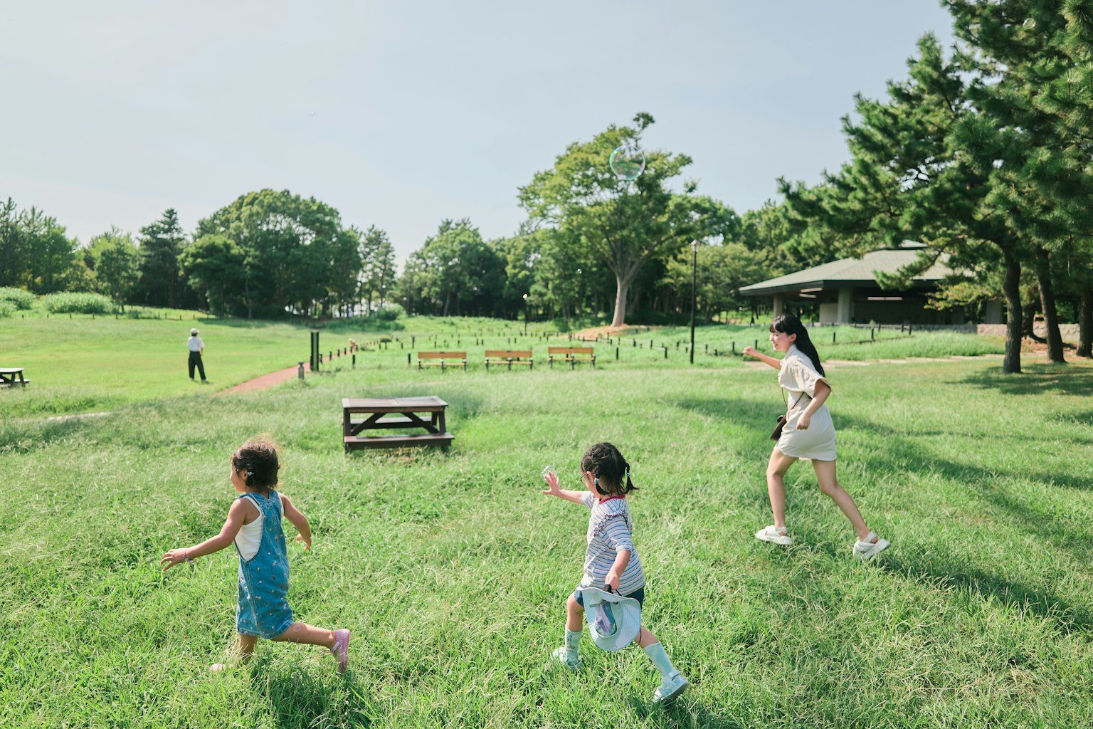 在綠色公園裡和一位女性一起奔跑的孩子們