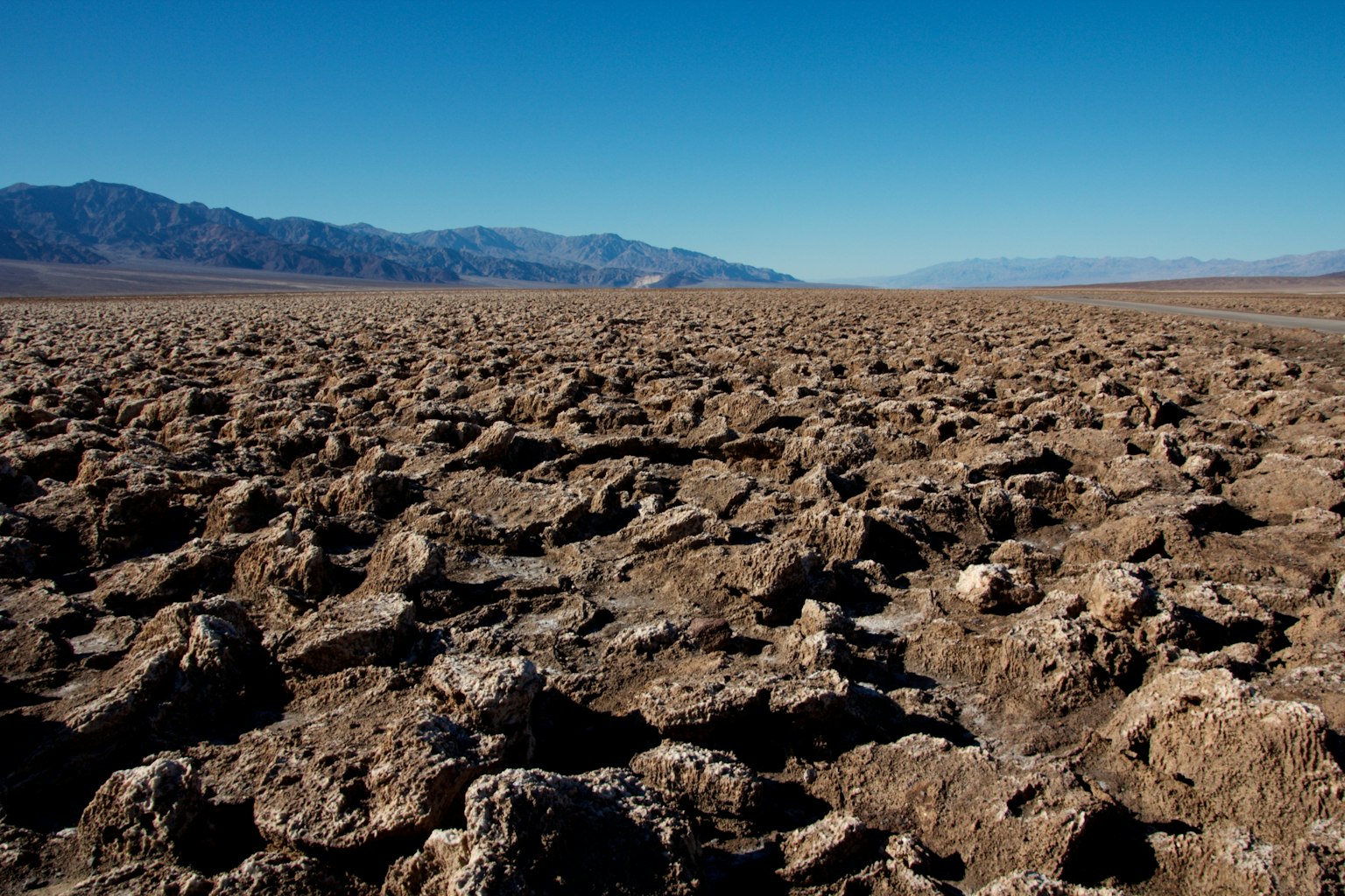 Paesaggio desertico secco con terreno roccioso e cielo blu chiaro