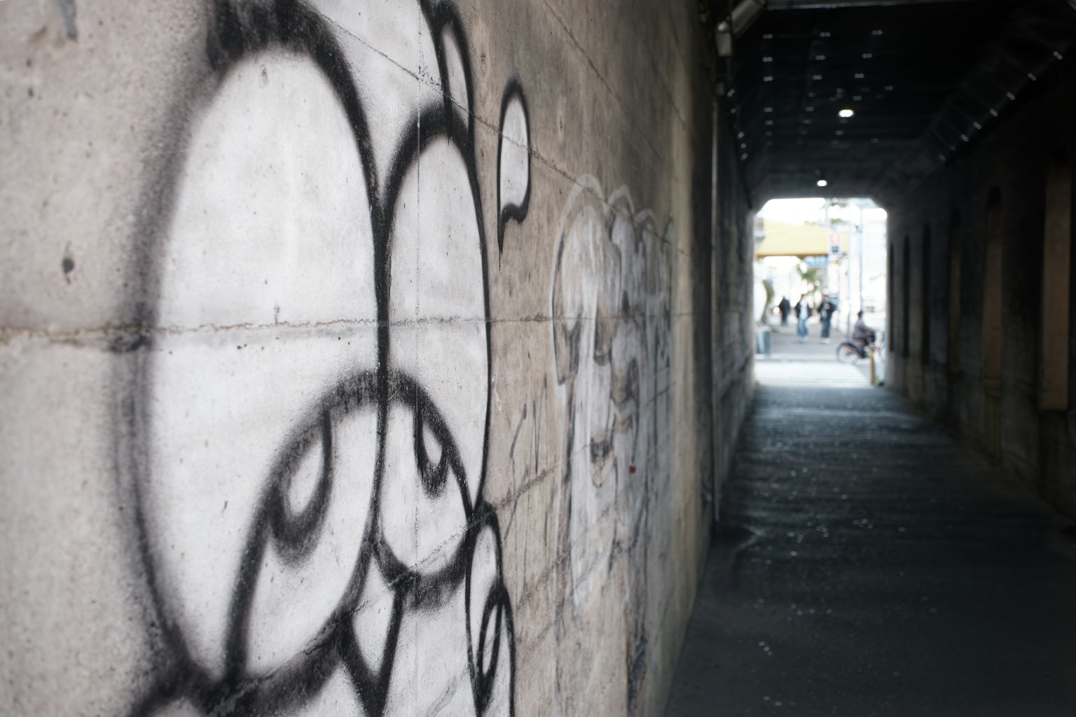 Vicolo stretto con graffiti sul muro e persone visibili in lontananza