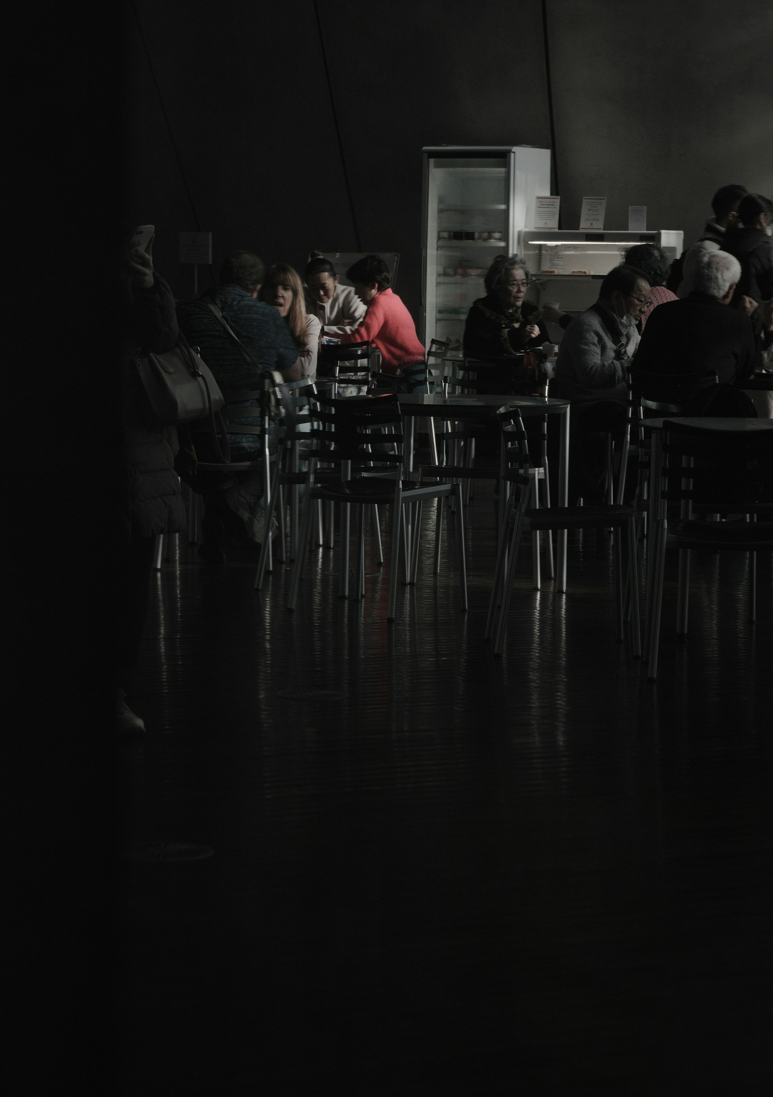 Grupo de personas sentadas en un área poco iluminada con suelo reflectante