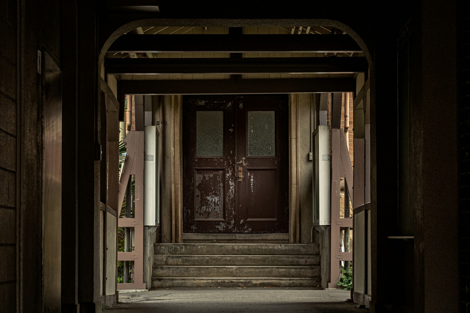 Dunkler Flur, der zu einer alten Holztür und einer Treppe führt