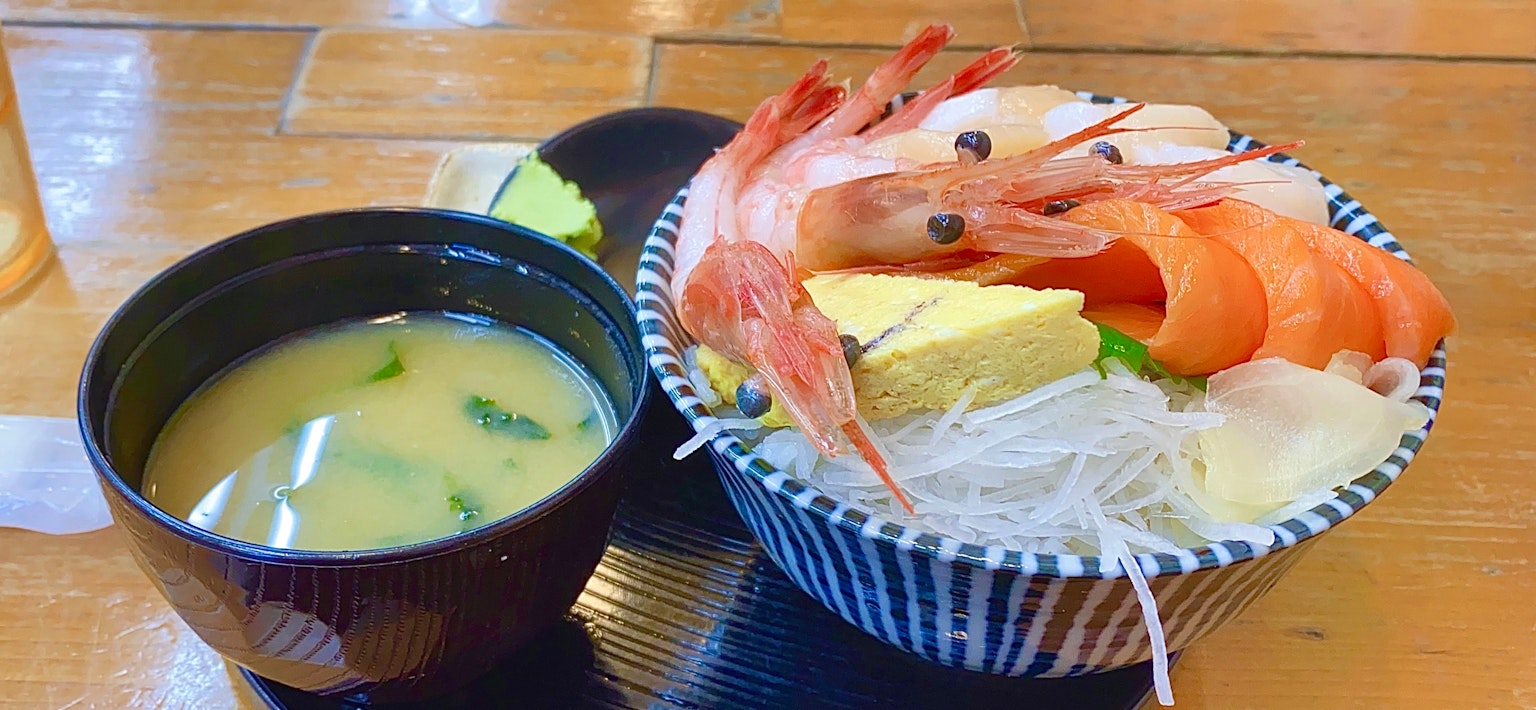 Una ciotola di riso ai frutti di mare guarnita con gamberi e una ciotola di zuppa di miso