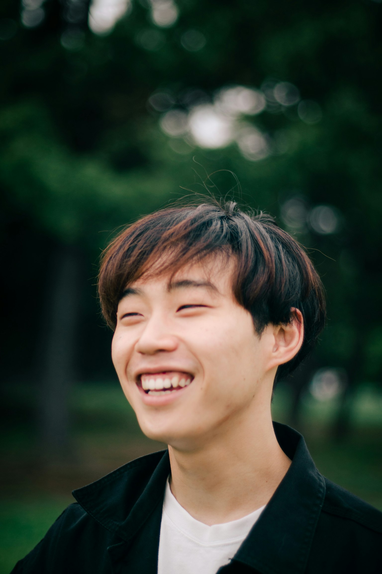 一位年轻男子在公园里微笑，沐浴在自然光中