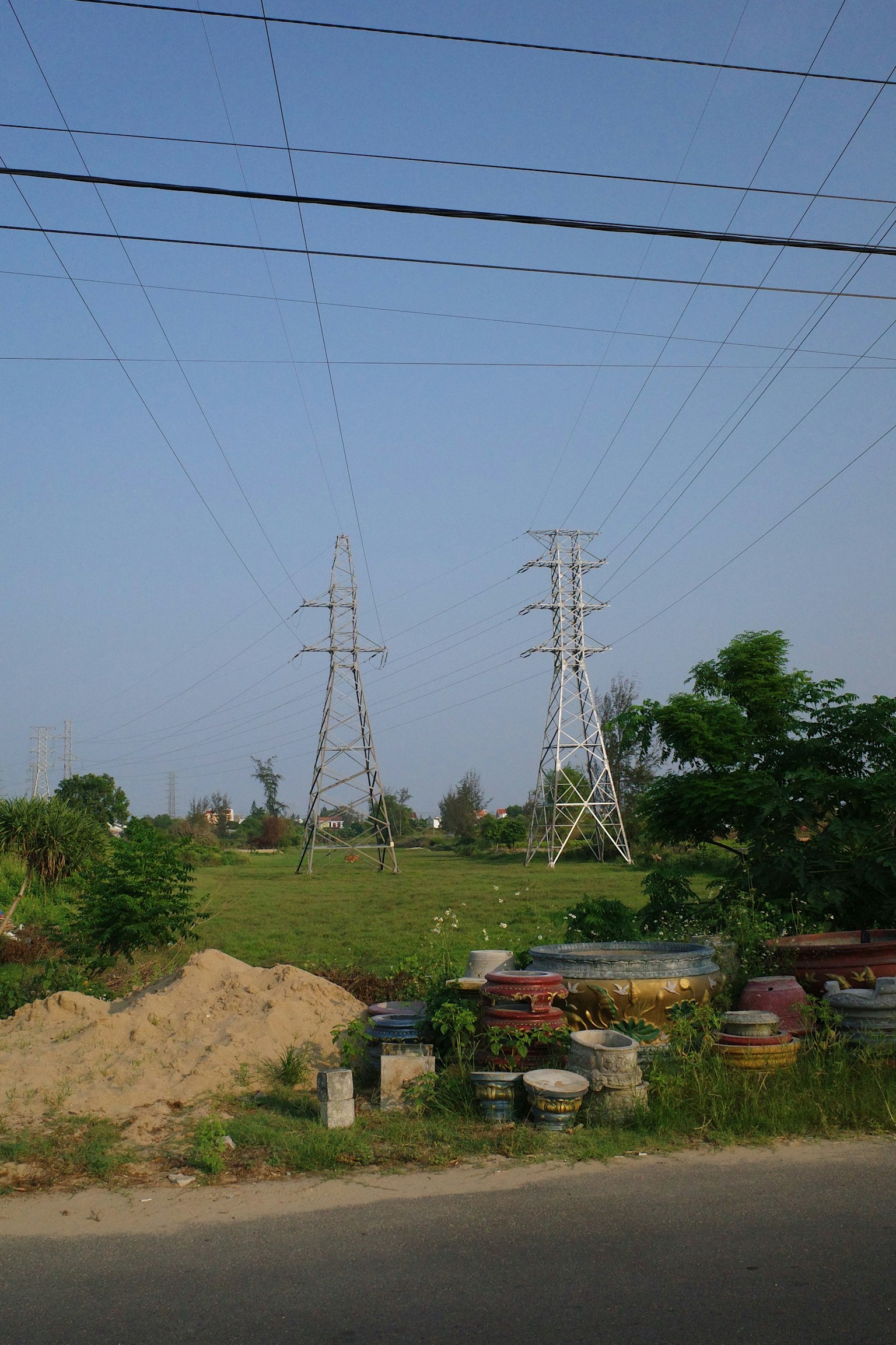 Pemandangan dengan saluran listrik tegangan tinggi dan menara, padang rumput dan gundukan tanah