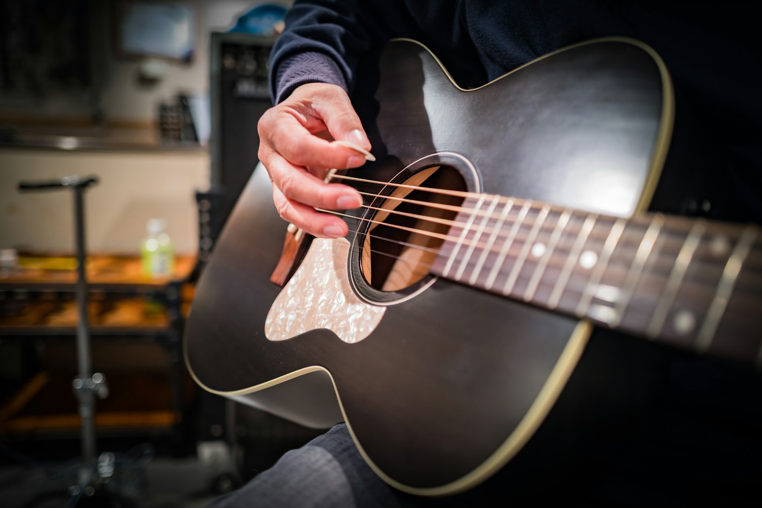 Kedekatan tangan yang memainkan gitar akustik hitam