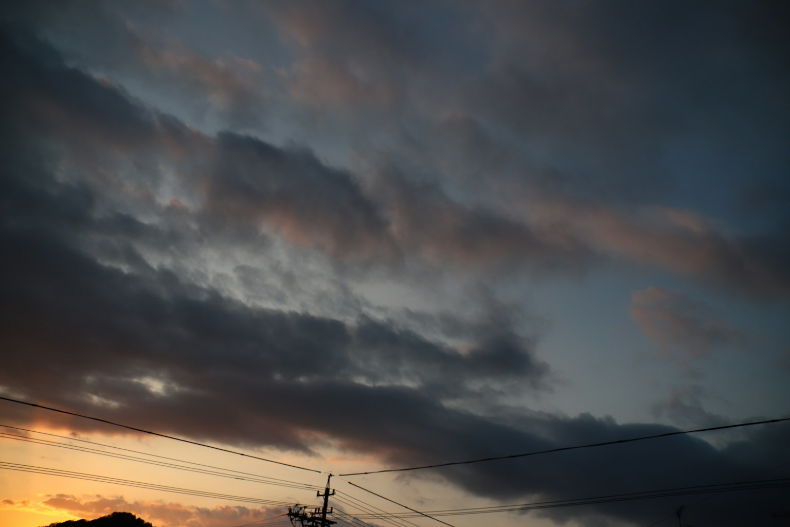 Silhouette de nuages dans un ciel au coucher du soleil avec des lignes électriques