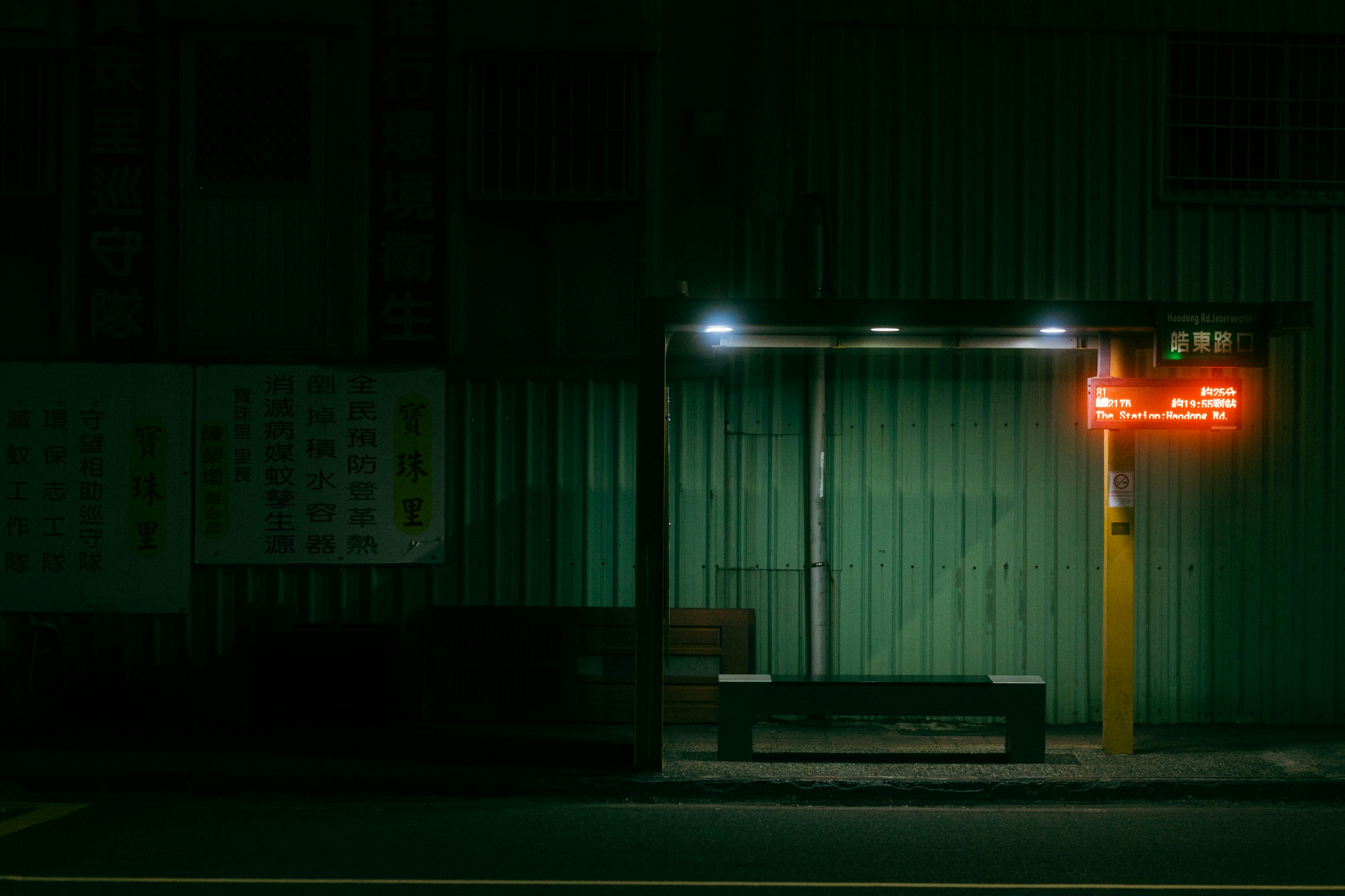 夜の街角にある無人のバス停のベンチと看板のある停留所