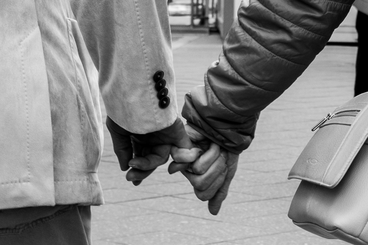 due persone che si tengono per mano all’angolo di una strada