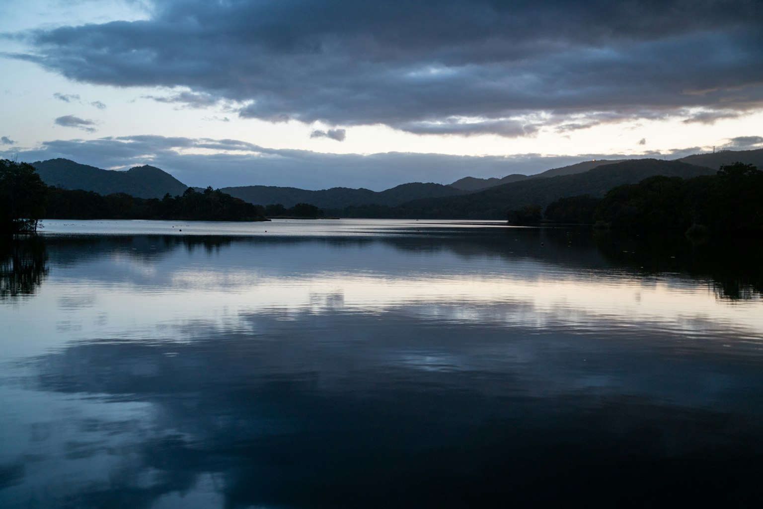 Paesaggio sereno di lago e montagne nuvole che si riflettono al crepuscolo