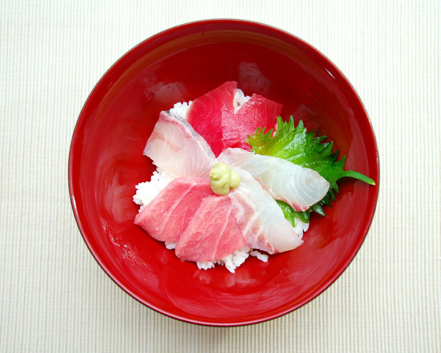 Sashimi cantik disusun di atas nasi dalam mangkuk merah
