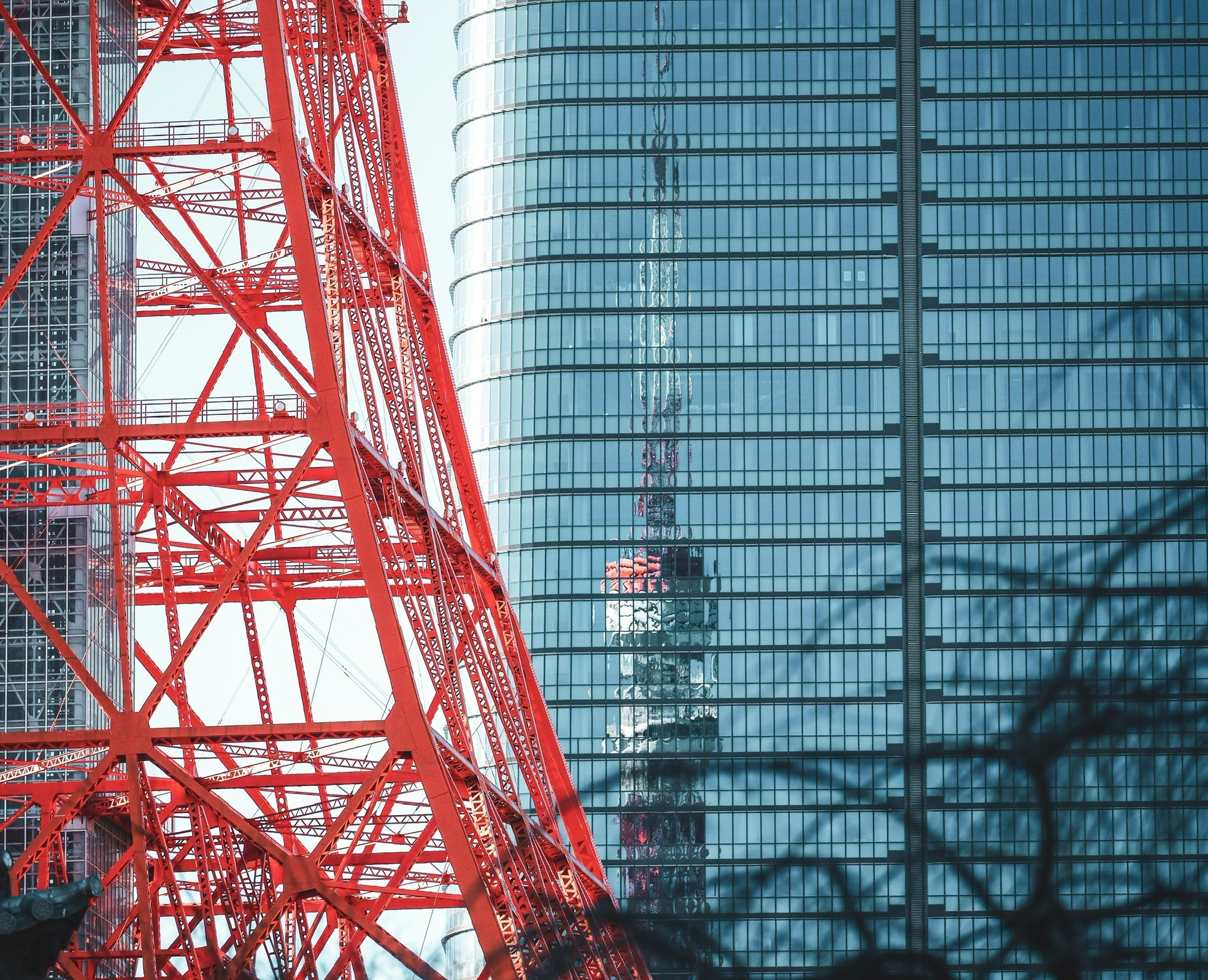 赤い鉄骨のタワーとガラス張りの高層ビルの対比