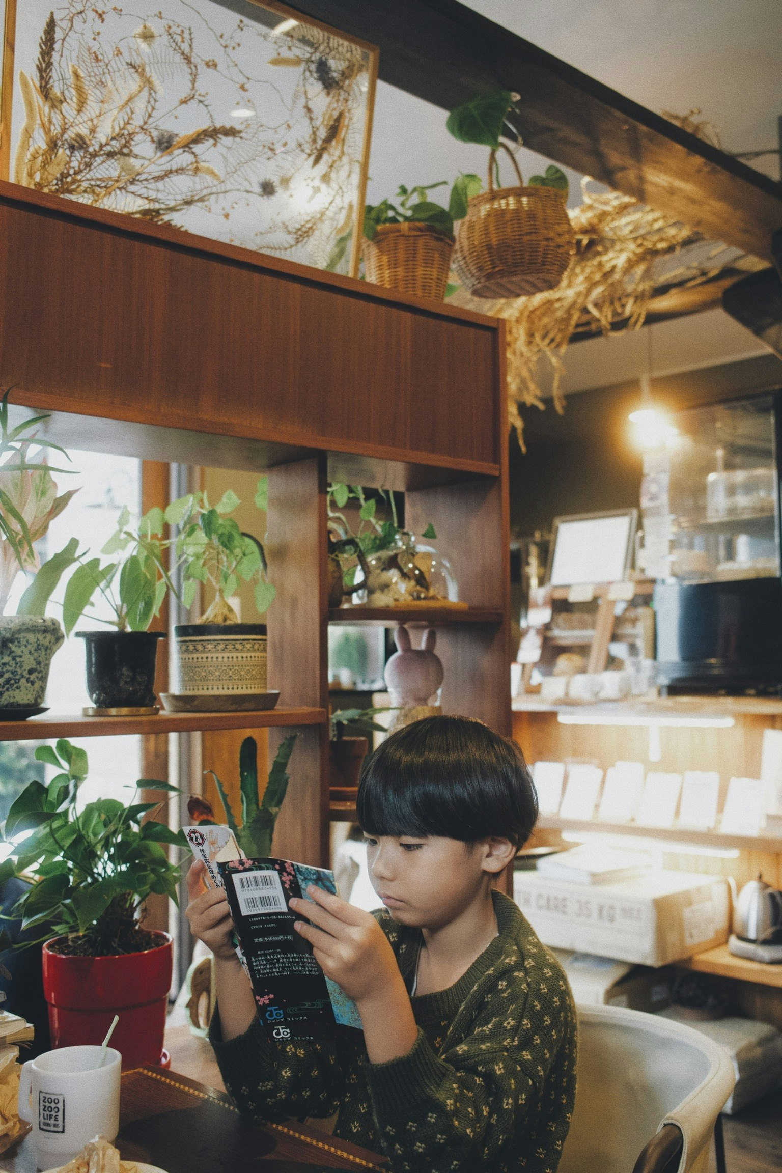 読書をする子どものいるカフェ店内の棚と小物のある風景