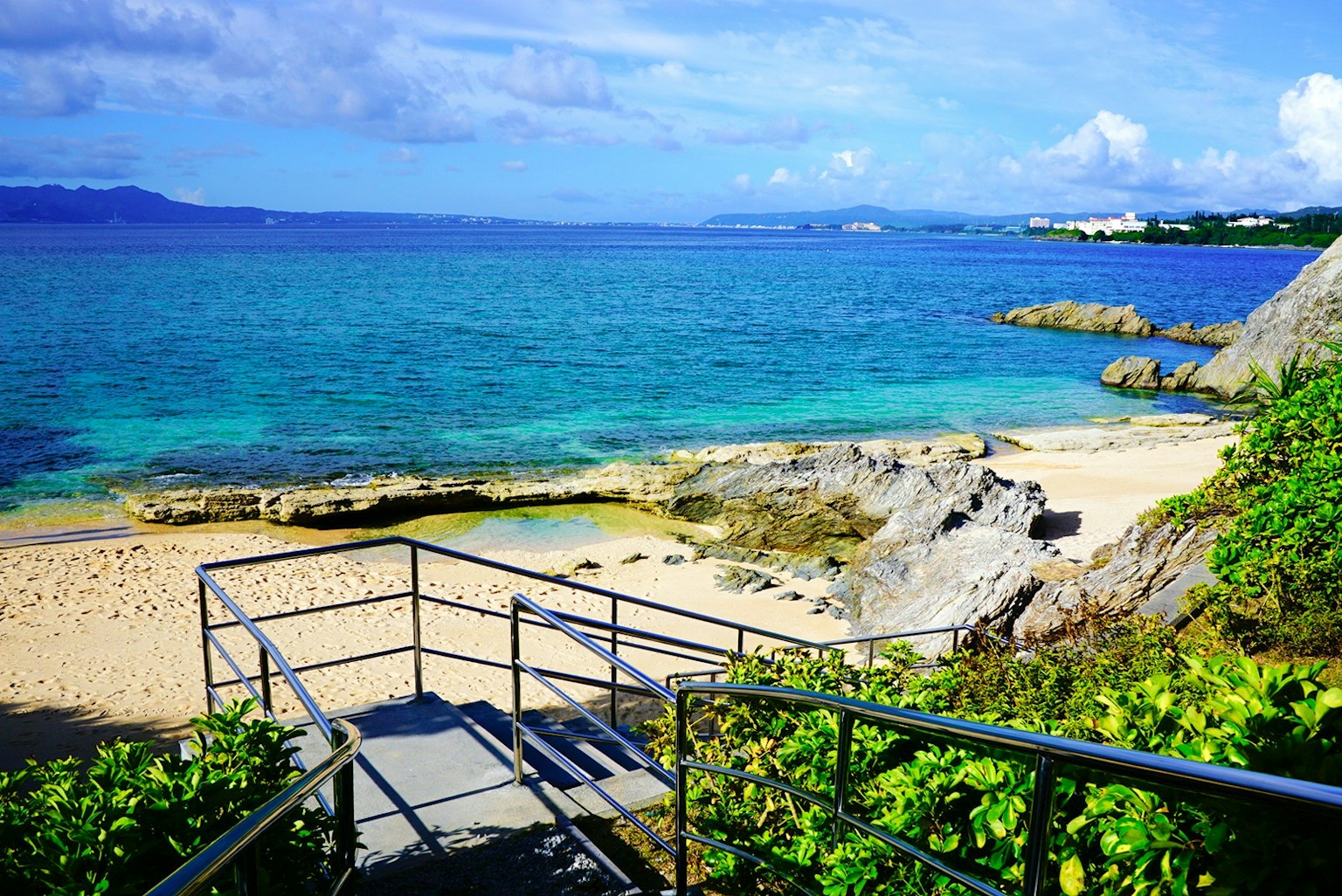 蓝色海洋和白色沙滩的风景 有楼梯和岩石的特点