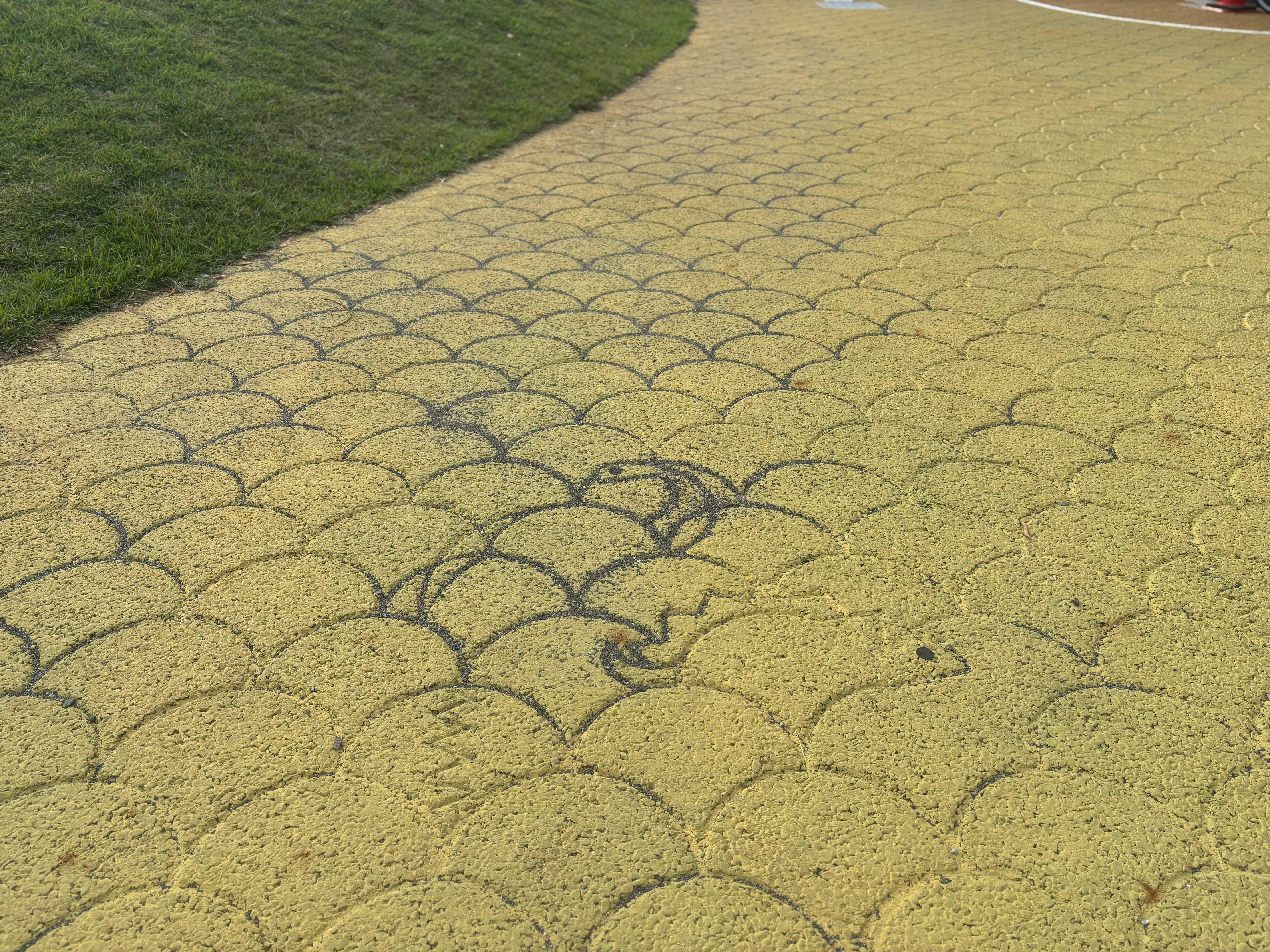 芝生の縁に広がる波形の舗装路