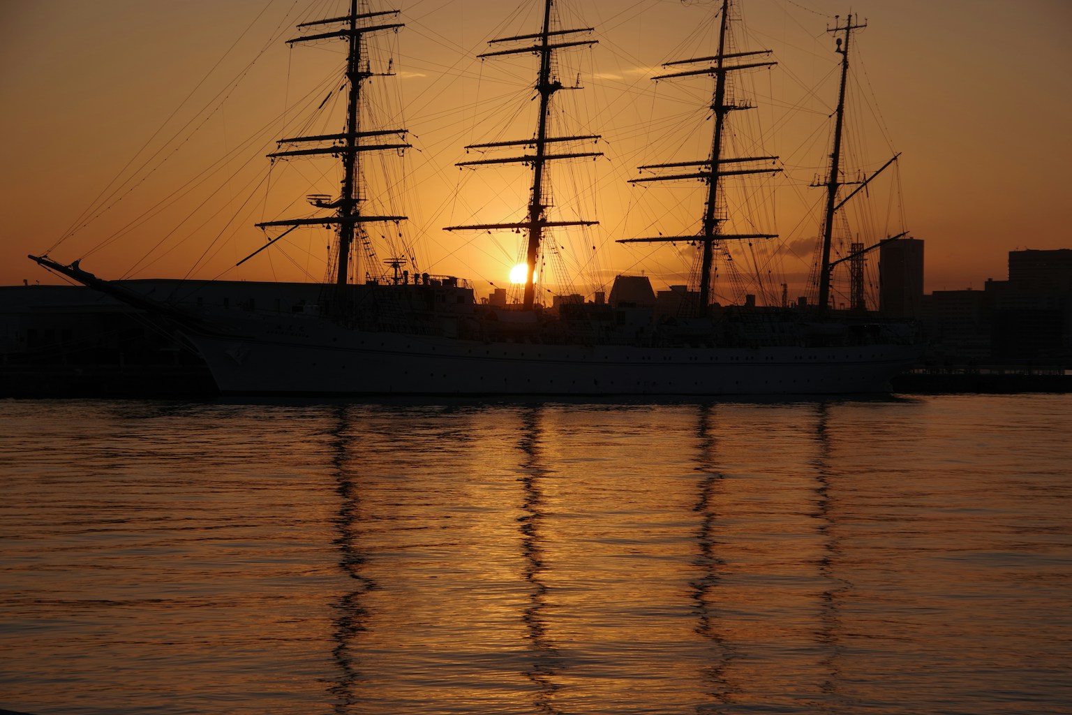 Silhouette of a sailing ship against the sunset with reflections on the water