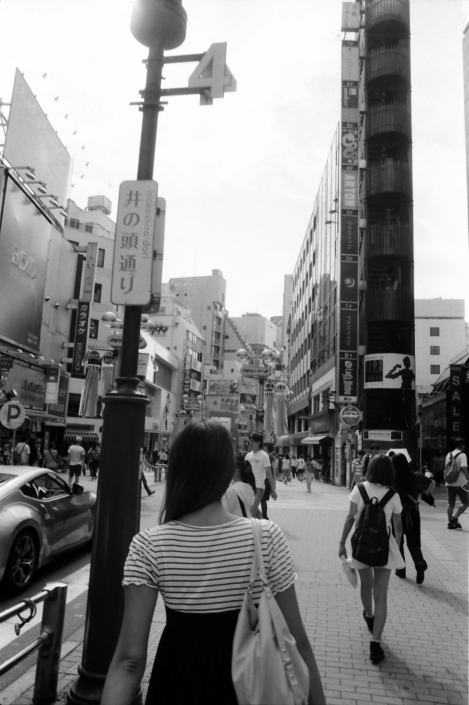 Black and white city scene featuring a woman walking away High-rise buildings and busy street atmosphere