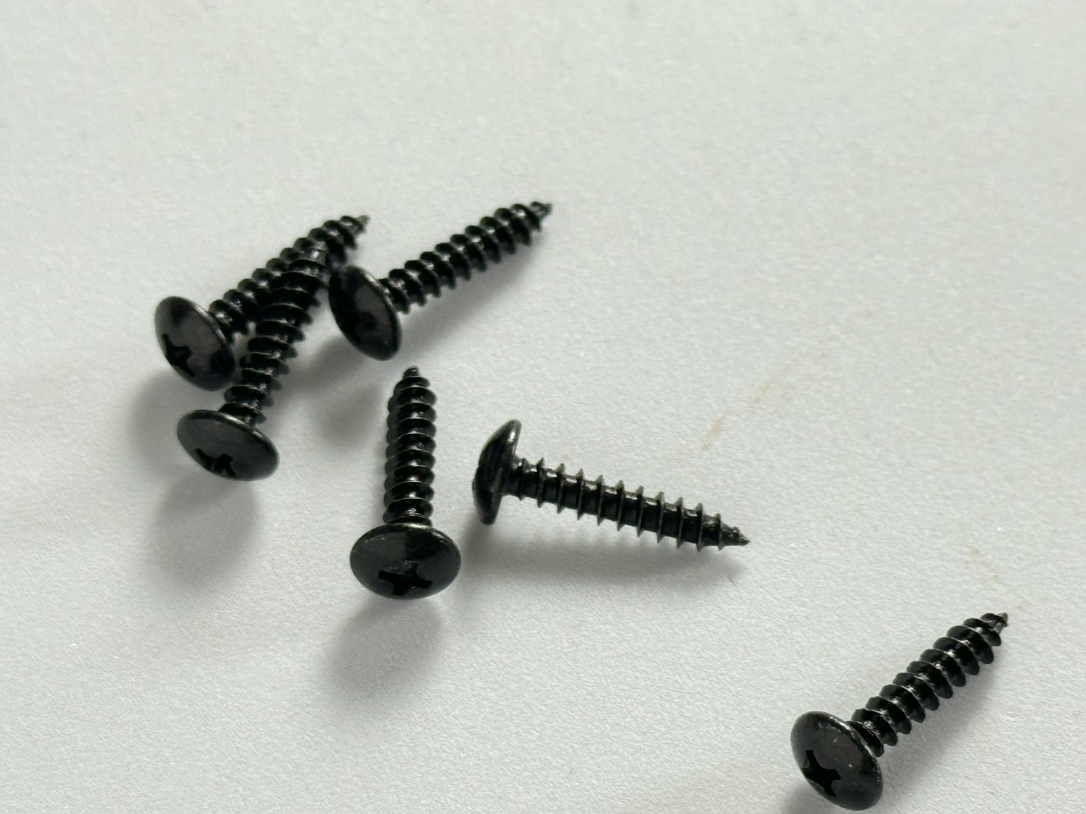 Quelques vis noires éparpillées sur une surface blanche