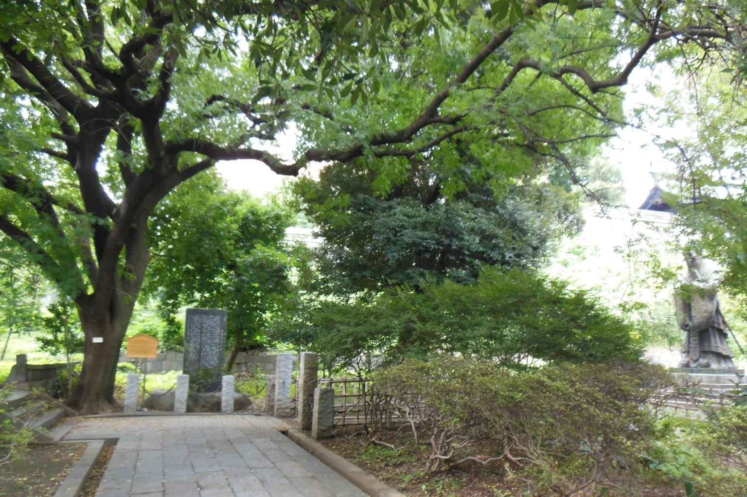 Jalan indah di taman hijau rimbun dengan monumen batu dan patung