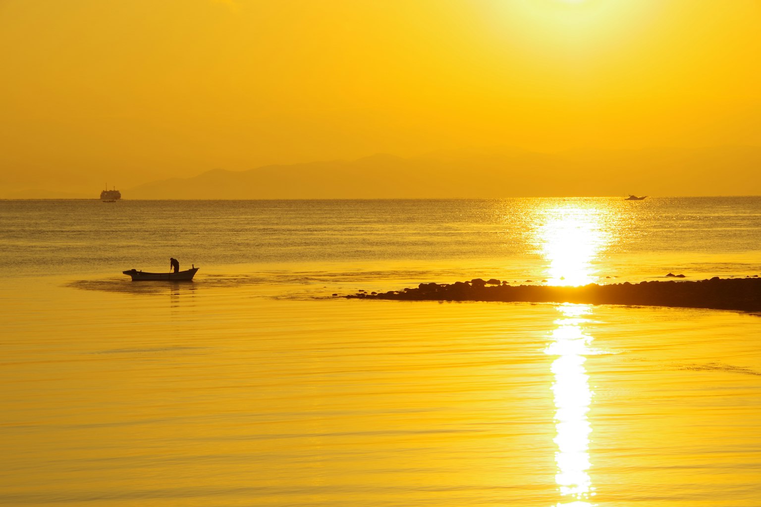 Wunderschöner Sonnenuntergang über dem ruhigen Ozean mit einem kleinen Boot